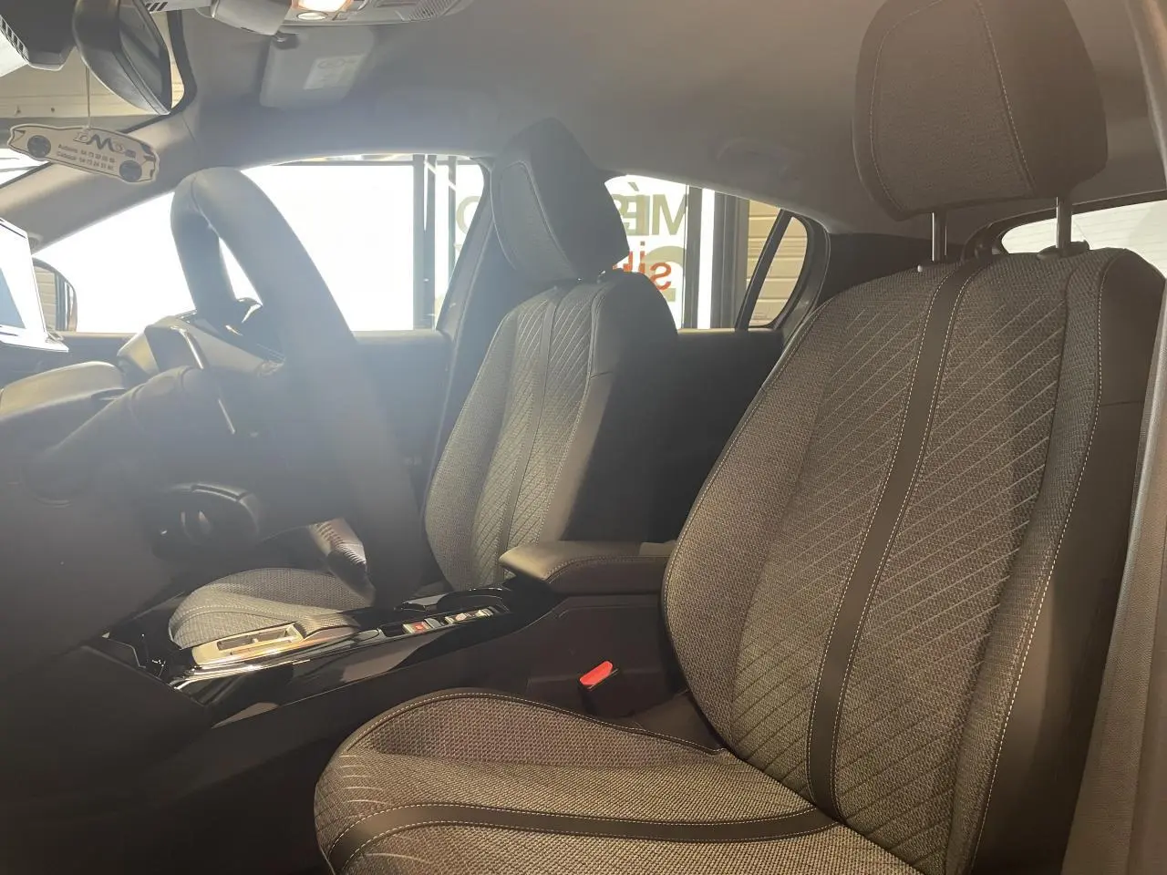 Intérieur de la Peugeot 208 2025, vue côté droit sur les sièges avant en tissu gris avec surpiqûres Quartz.