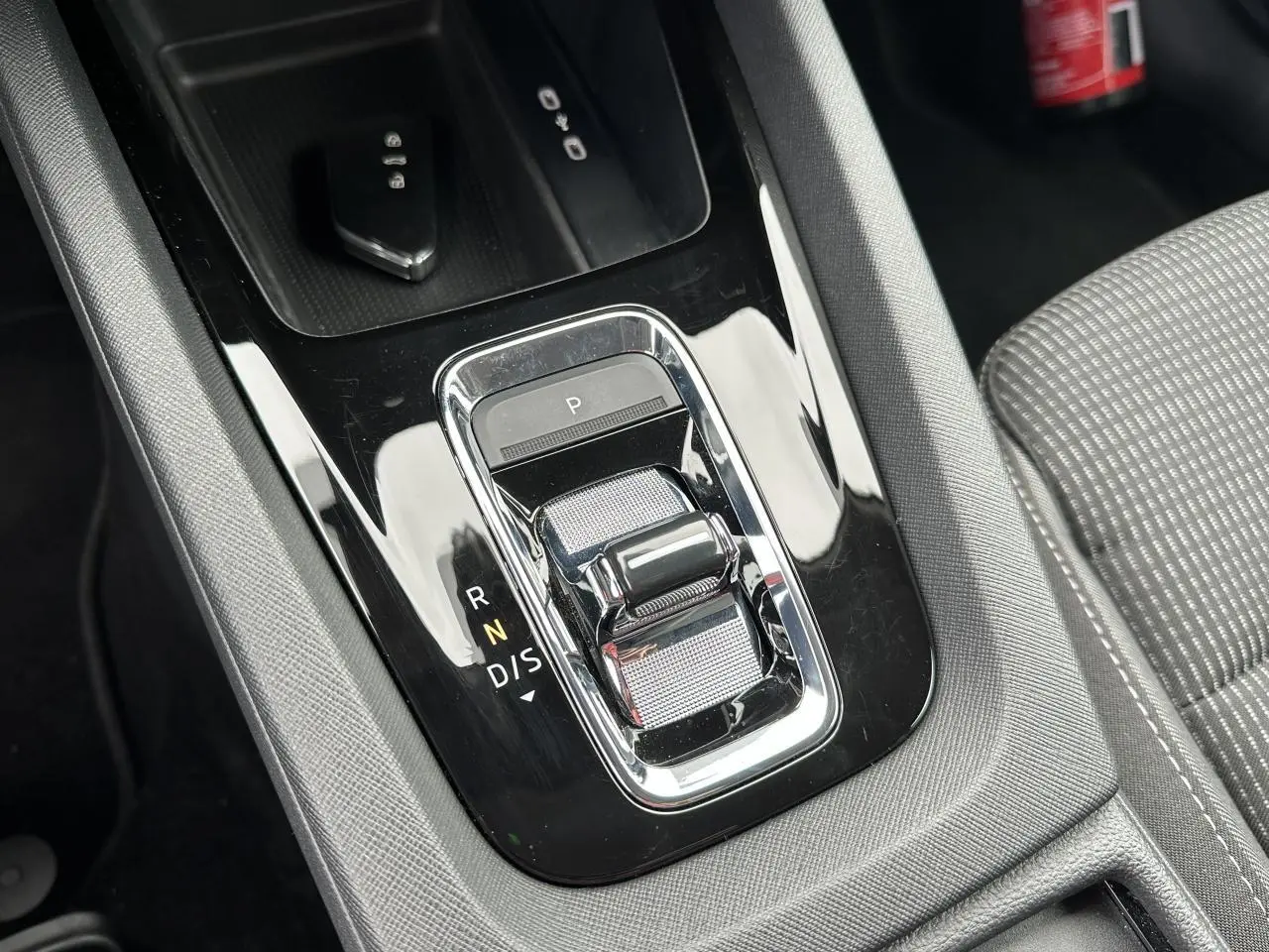 Gros plan sur la console centrale noire brillante de la Skoda Octavia Combi 2024 avec levier de boîte automatique et siège tissu gris.