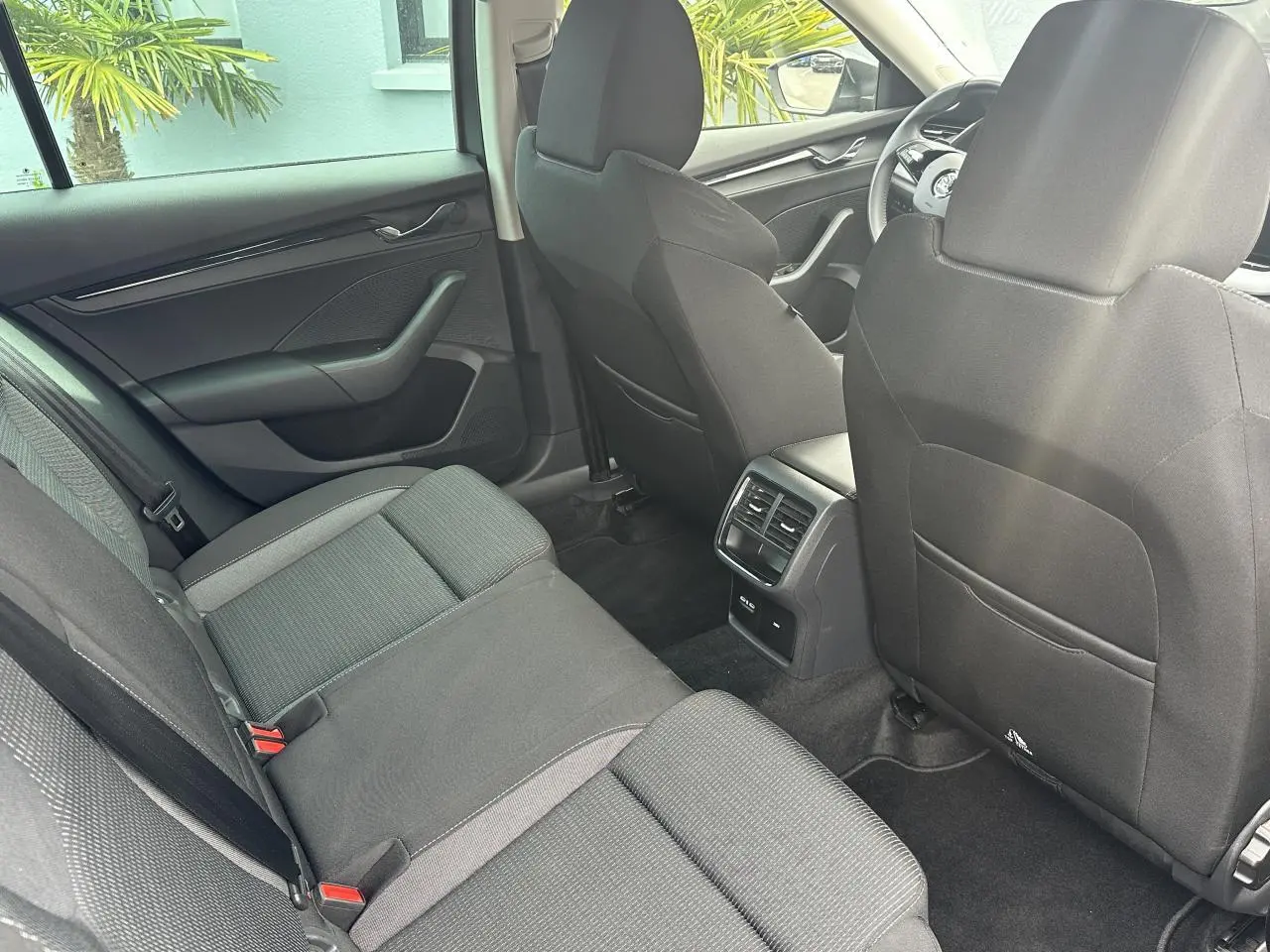 Vue intérieure arrière de la Skoda Octavia Combi gris graphite, montrant les sièges arrière et la console centrale avec aérateurs.