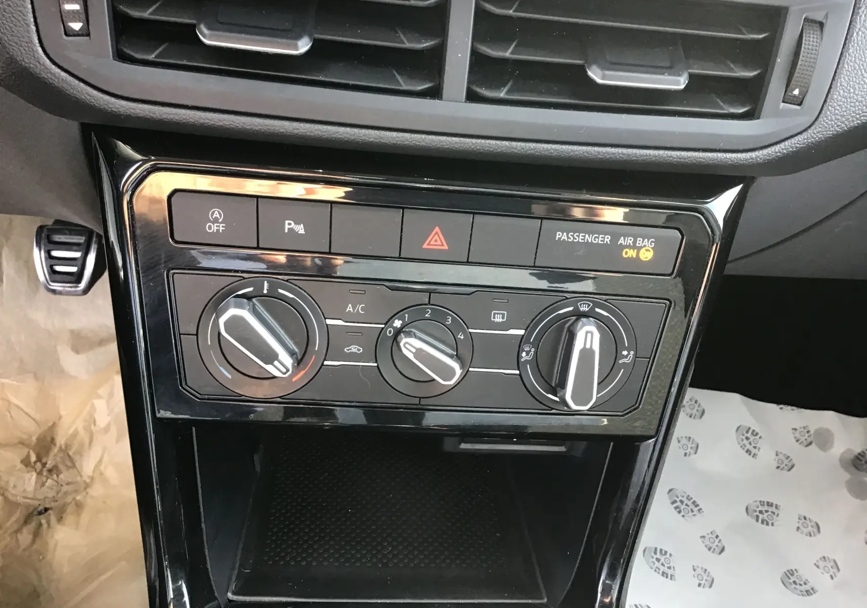 Vue rapprochée du tableau de commande de climatisation et des boutons de sécurité d’un Volkswagen T-Cross blanc de 2021.