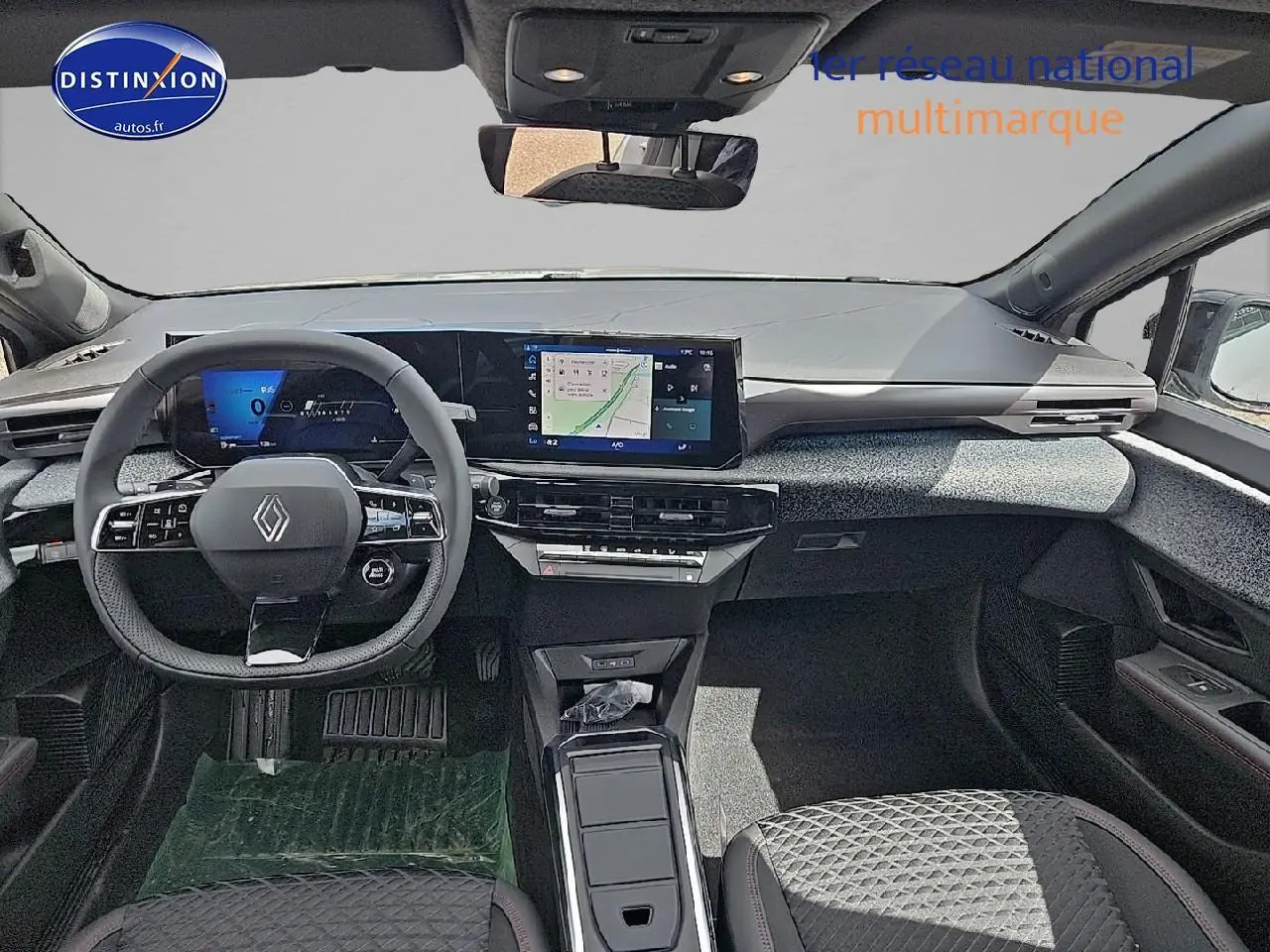Vue intérieure avant de la Renault Clio VI gris rafale, tableau de bord moderne avec écran tactile et volant multifonctions.