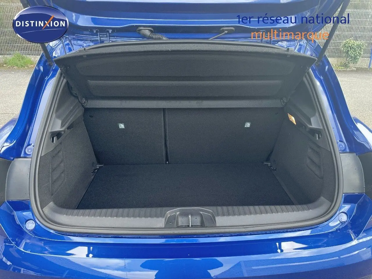 Coffre ouvert d'une Renault Clio TCe 90ch Techno bleu Iron Metal, vue arrière montrant l'espace de chargement vide.