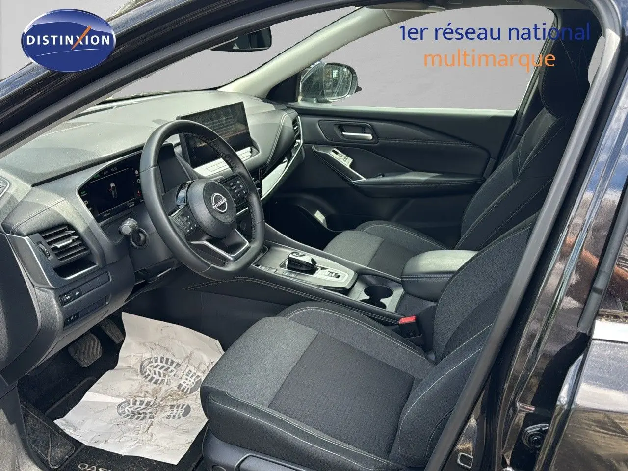 Intérieur avant droit du Nissan Qashqai 2024 noir, avec tableau de bord moderne et sièges tissu gris.