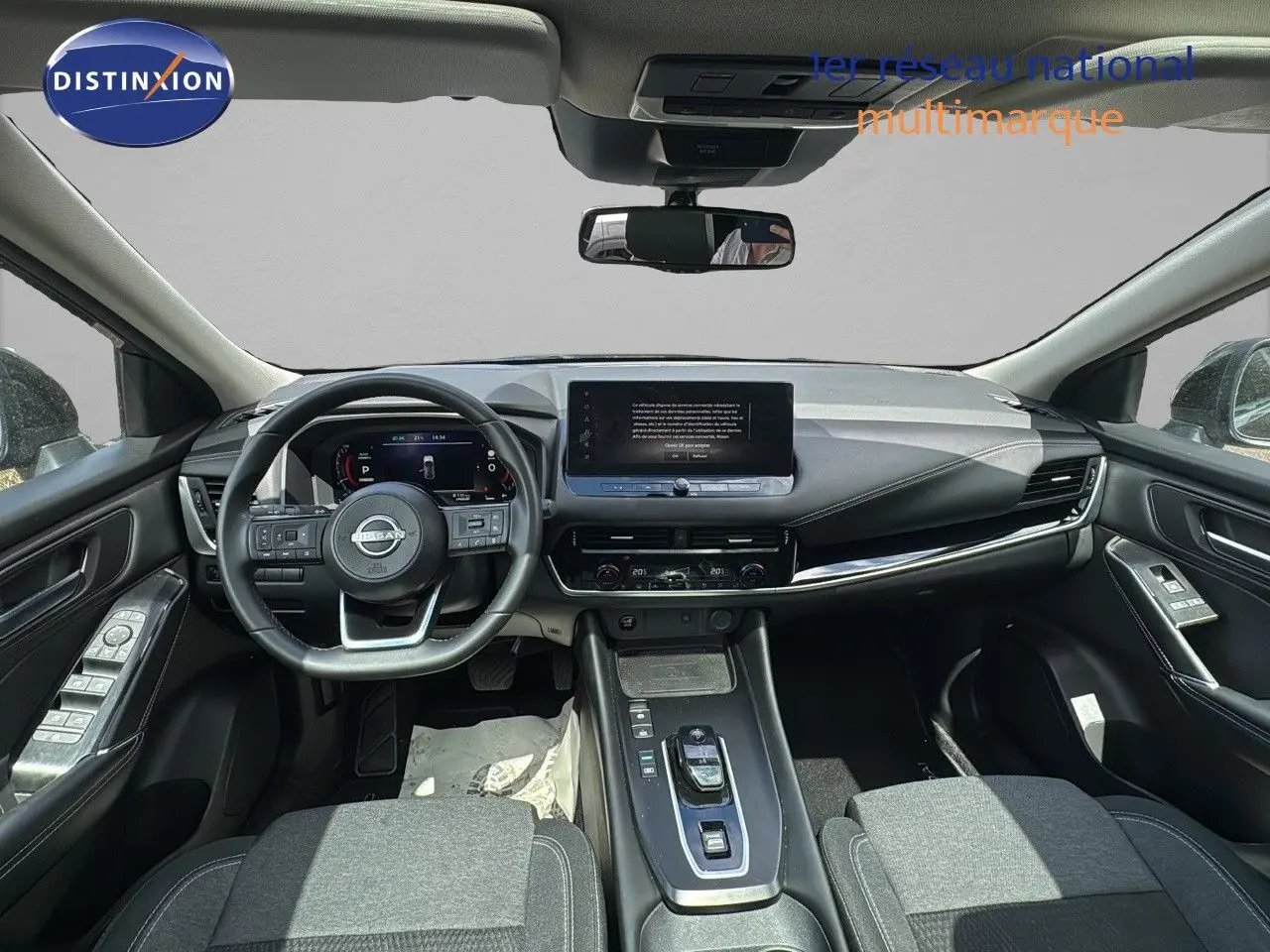 Vue intérieure avant du Nissan Qashqai 1.5 e-Power 2024, tableau de bord moderne avec écran tactile central et volant multifonction noir.