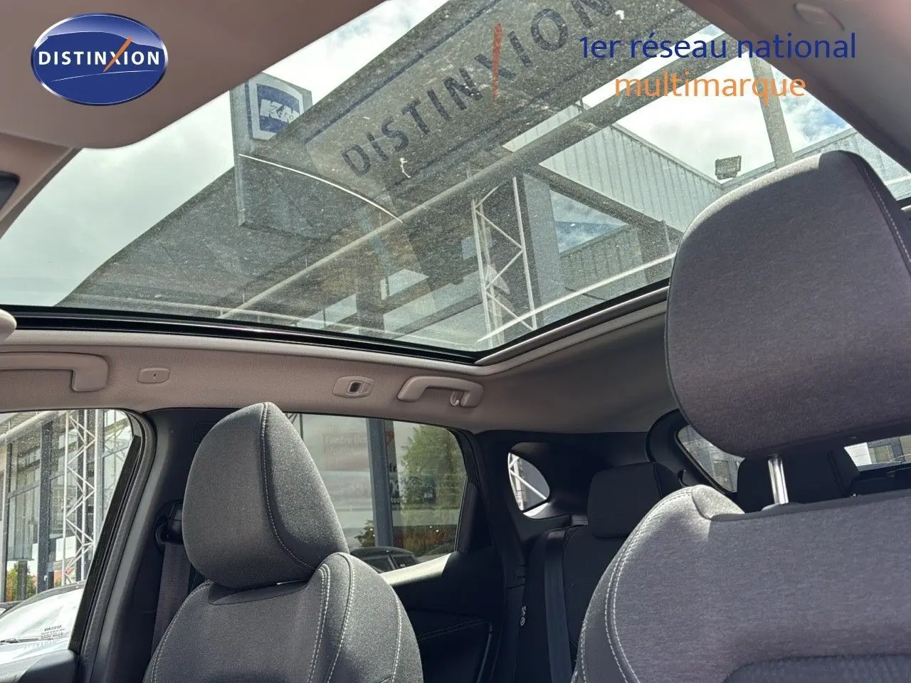 Vue intérieure du Nissan Qashqai 2024 noir, montrant les sièges avant et le toit ouvrant panoramique en verre.