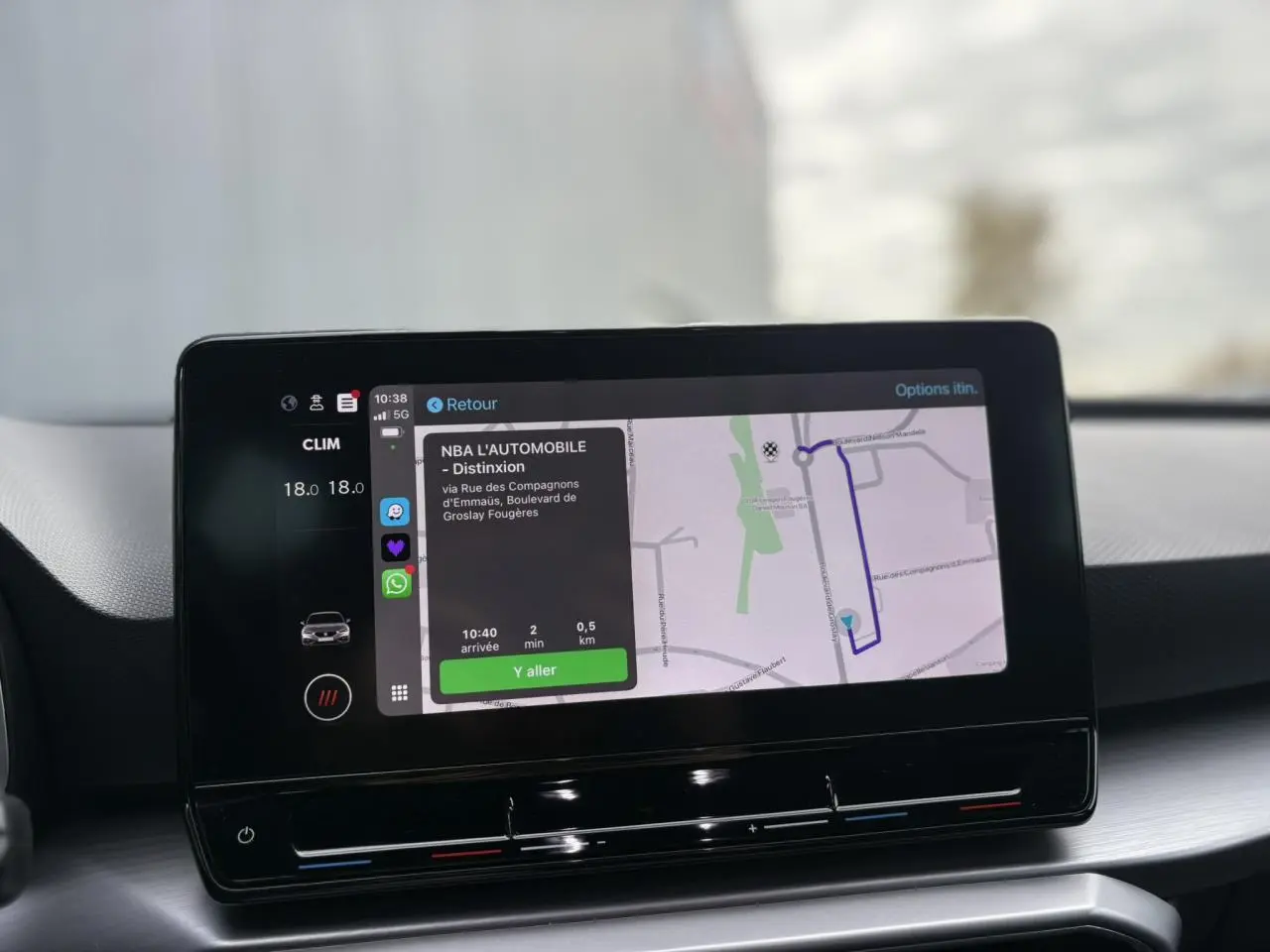 Écran tactile 10 pouces du système de navigation SEAT Leon 2024 affichant un itinéraire et la climatisation à 18°C.