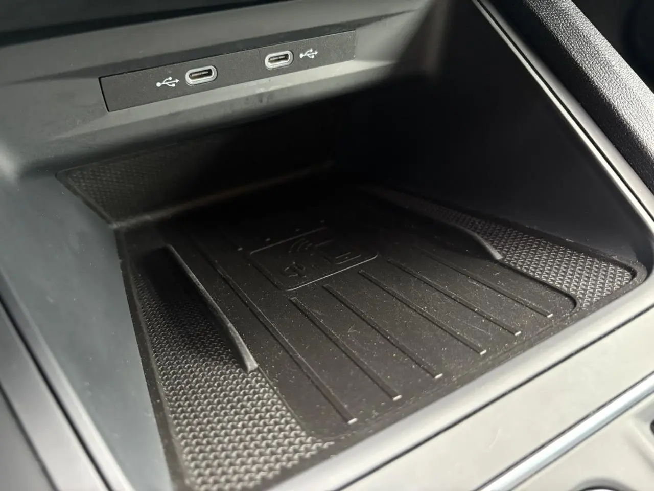 Gros plan sur la zone de recharge sans fil et ports USB-C du coffre central d'une SEAT LEON 1.5 e-TSI 150 DSG7 FR 2024.