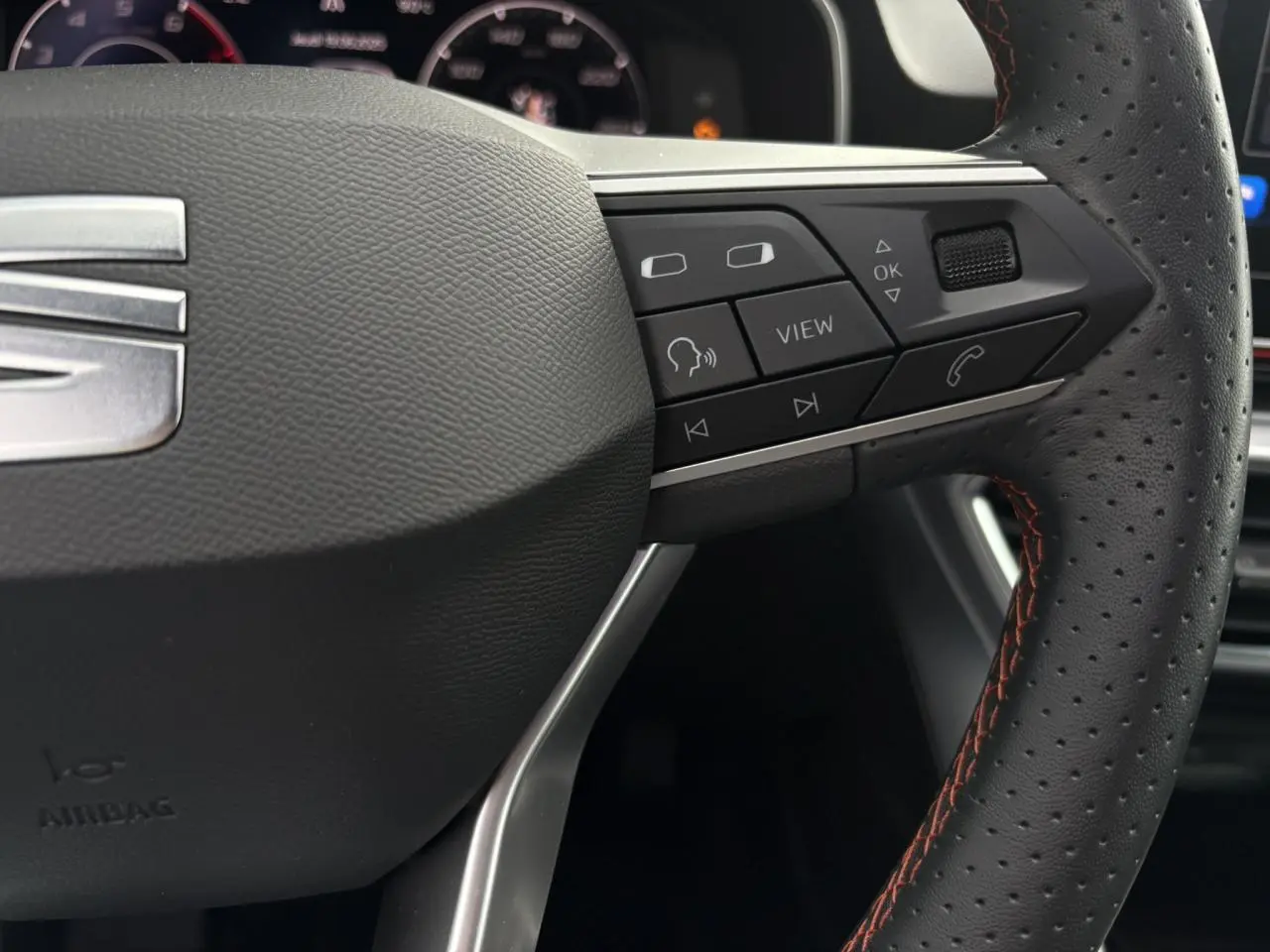 Gros plan sur le volant cuir perforé côté droit du SEAT LEON 1.5 e-TSI 150 DSG7 FR avec commandes multifonctions.