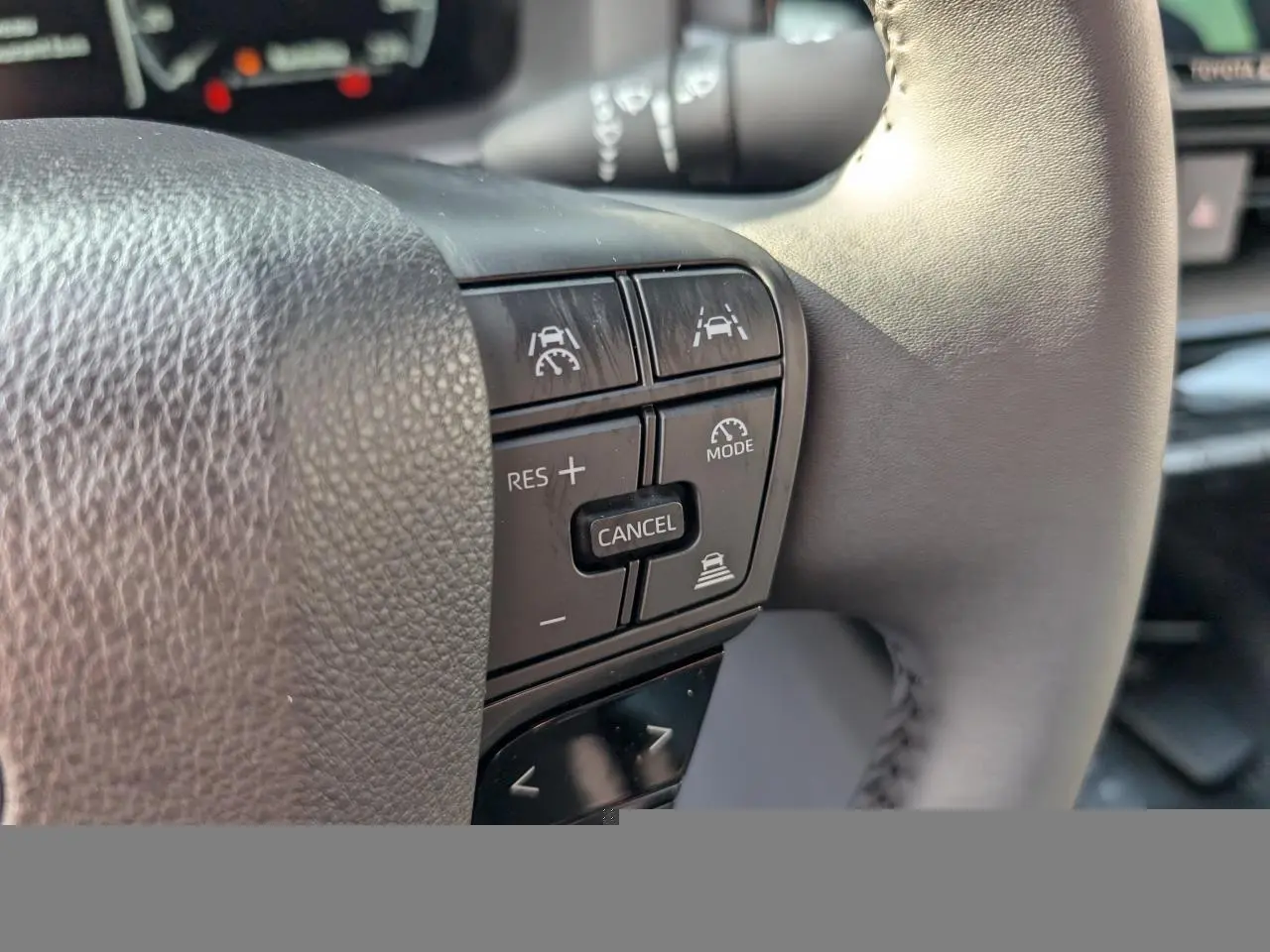 Gros plan sur les commandes du volant côté droit du Toyota C-HR 1.8 Hybrid blanc, boutons de régulateur et assistance.