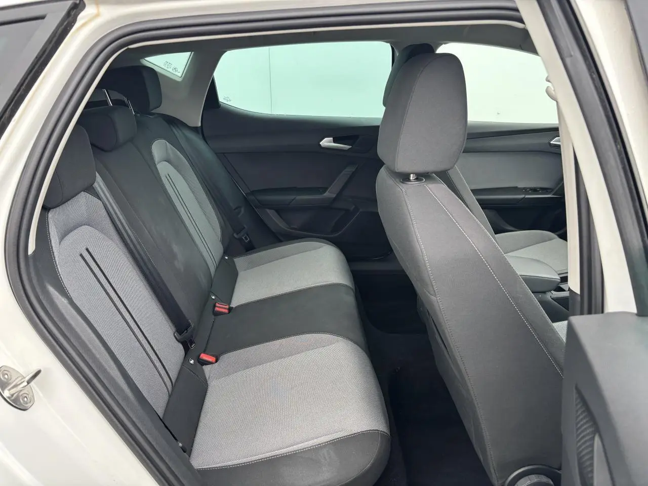 Vue intérieure côté gauche montrant la banquette arrière bicolore grise et noire d'une SEAT LEON blanche 2024.