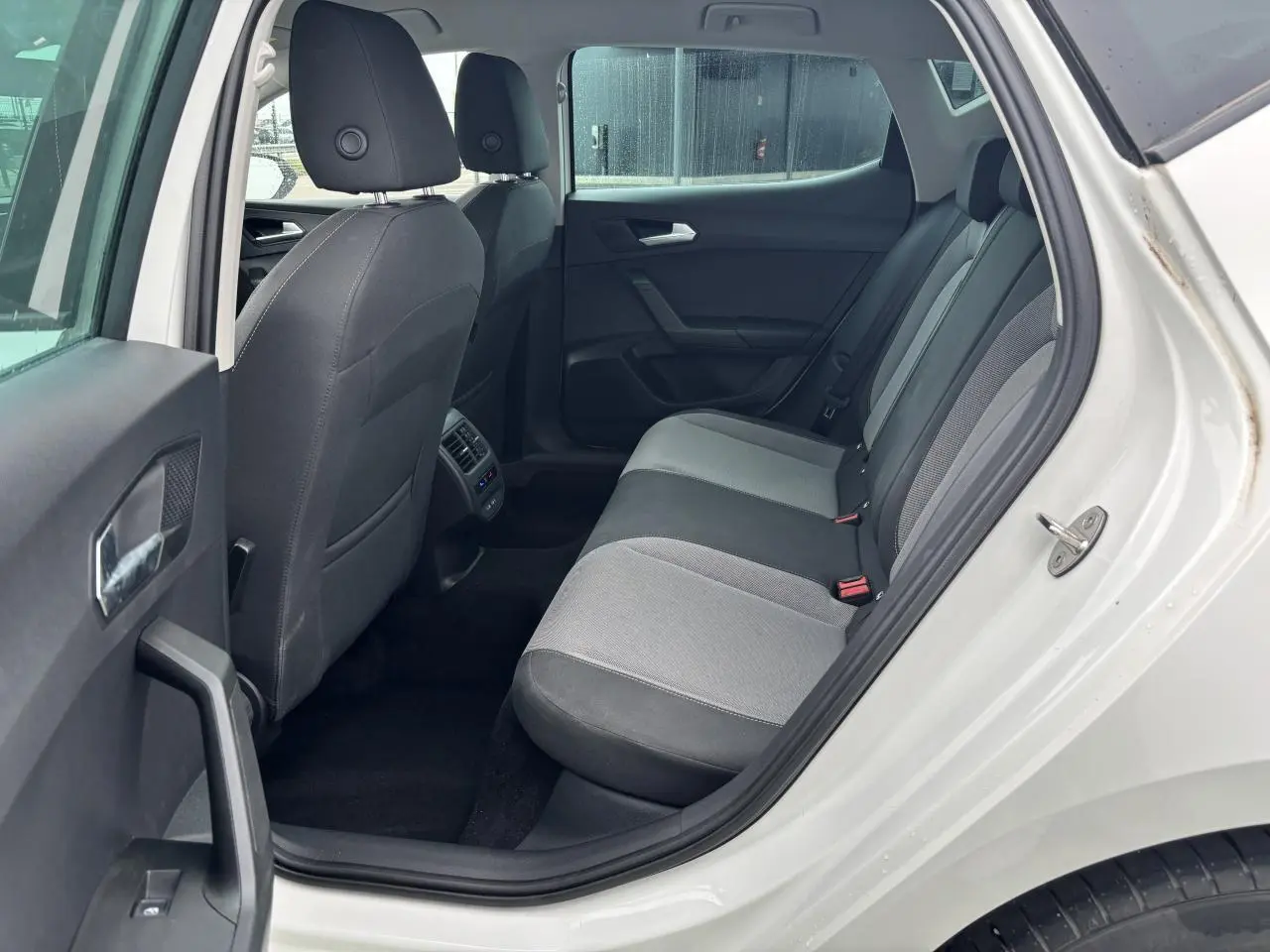 Vue côté gauche arrière du siège arrière gris et noir dans la SEAT LEON blanc 2024 avec portières ouvertes.