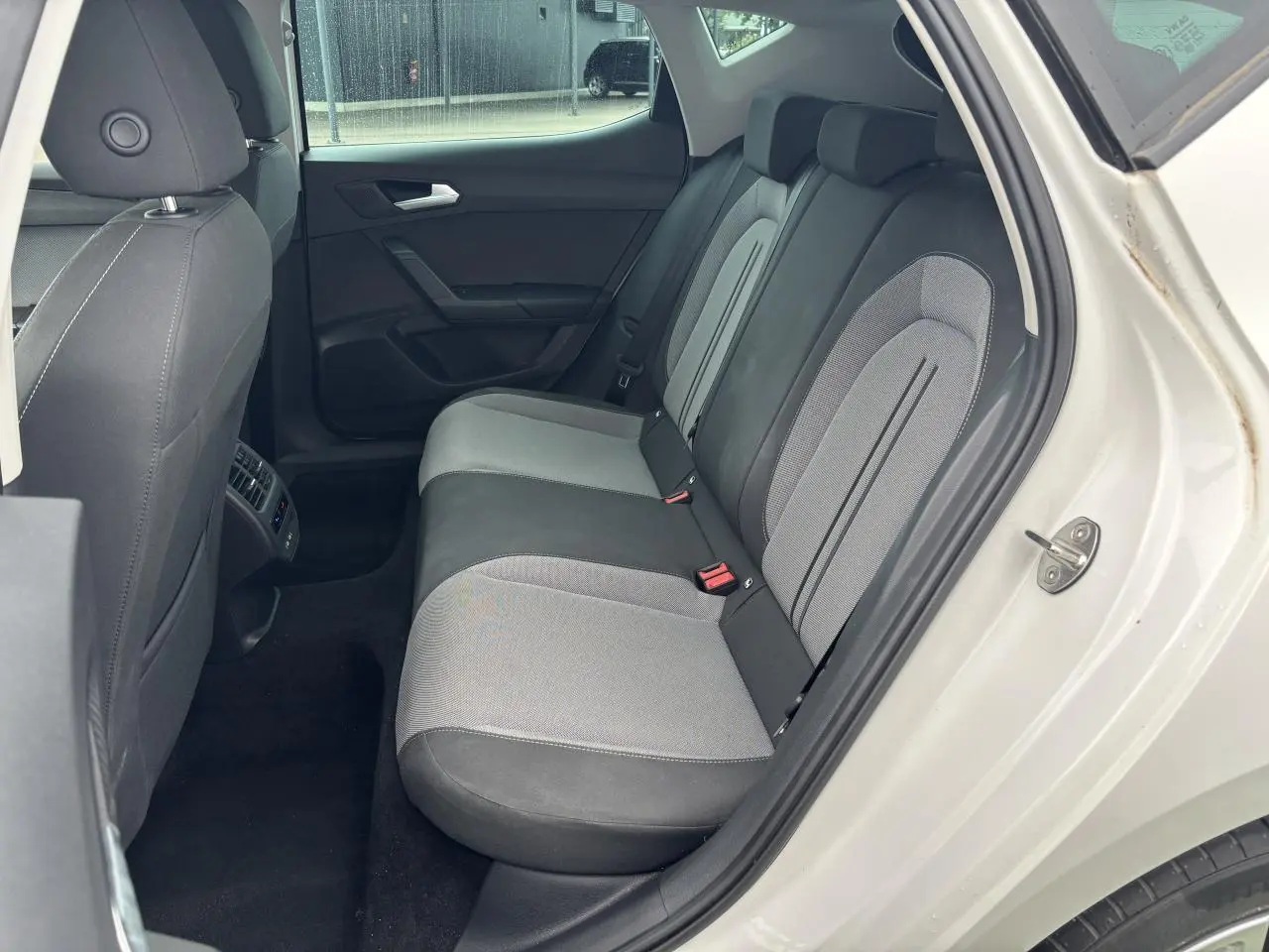 Vue côté droit arrière du siège arrière bi-ton gris et noir d'une SEAT LEON blanche 2024 avec porte ouverte.