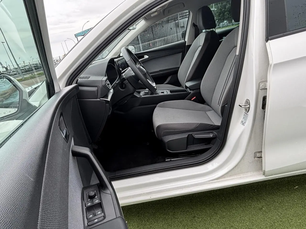Vue côté gauche intérieur d'une SEAT LEON blanche 2024, montrant les sièges avant et le tableau de bord moderne.