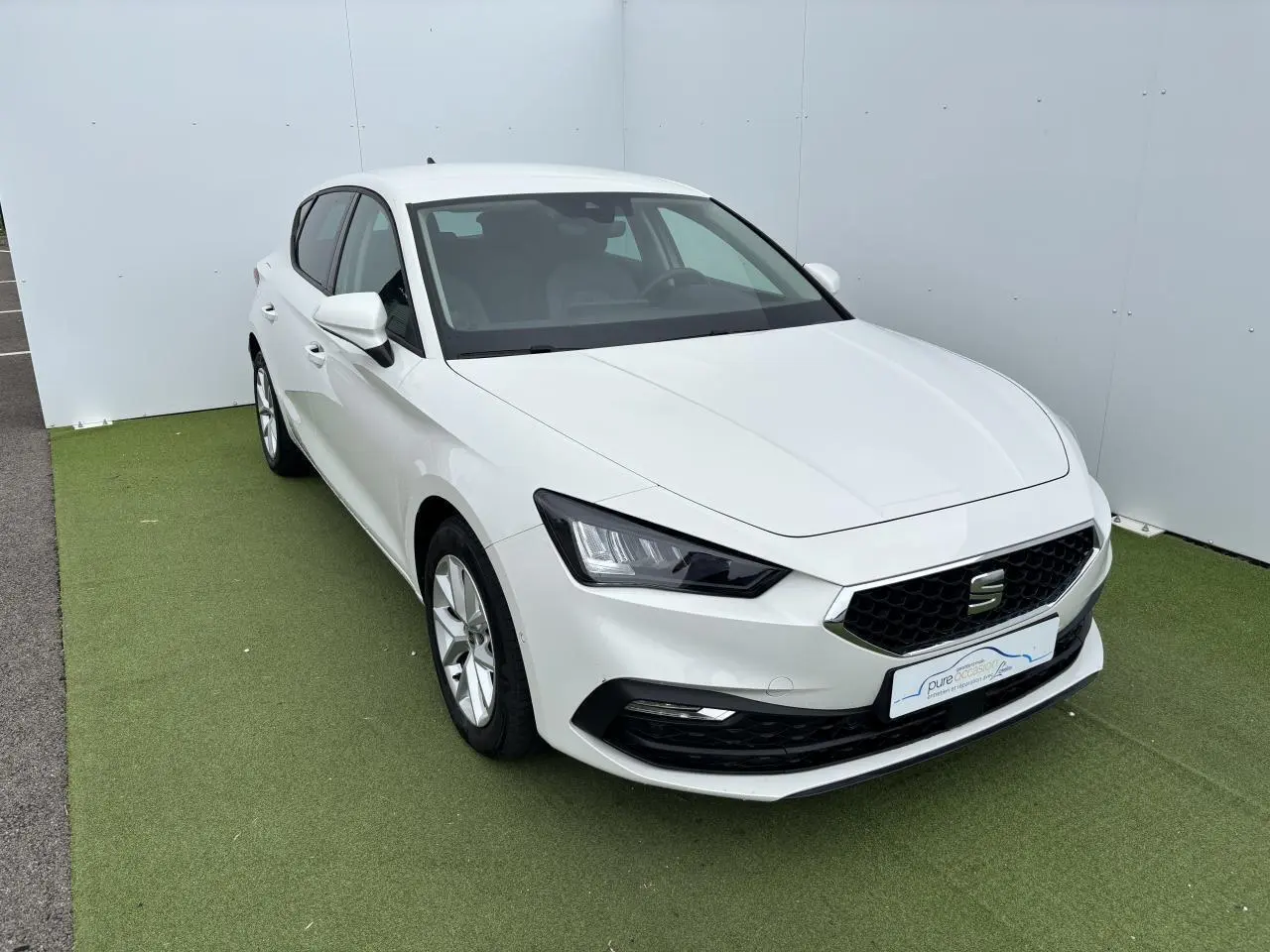 Vue 3/4 avant d'une SEAT Leon IV blanche avec jantes alliage 16 pouces et calandre hexagonale noire.