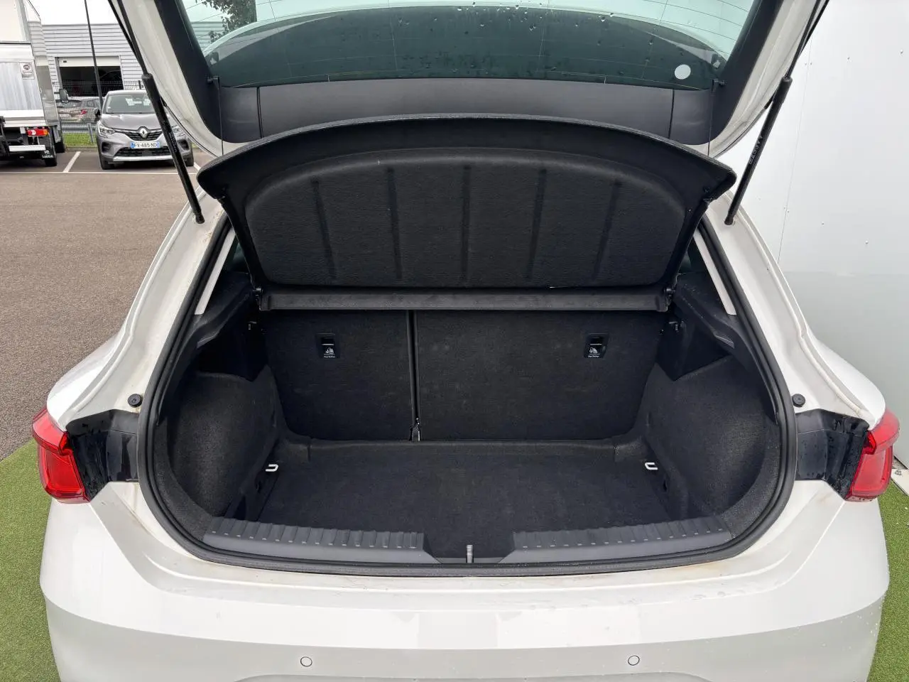 Coffre ouvert vu de l'arrière d'une SEAT LEON blanche 2024, montrant un espace de chargement propre et spacieux.