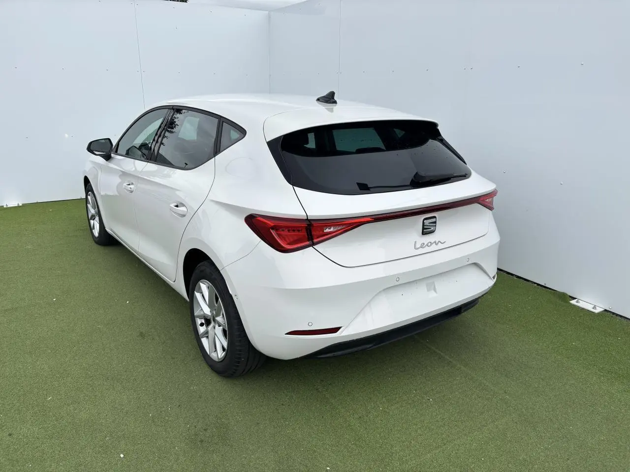 SEAT Leon blanc vue 3/4 arrière droit, avec feux arrière reliés par une bande lumineuse rouge.