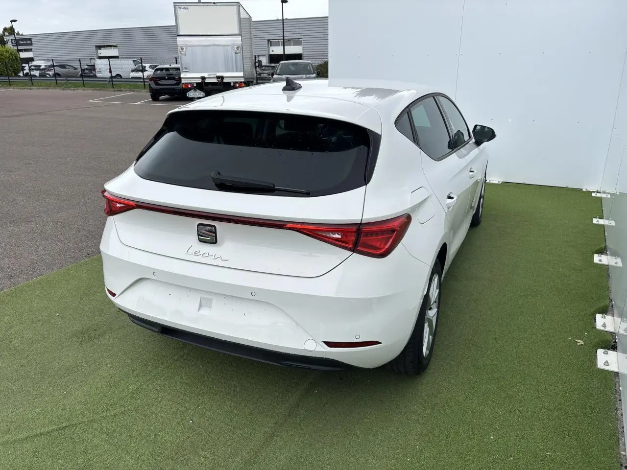 Vue 3/4 arrière droite d'une SEAT Leon blanche 2024 avec feux arrière LED et jantes alliage 16 pouces.