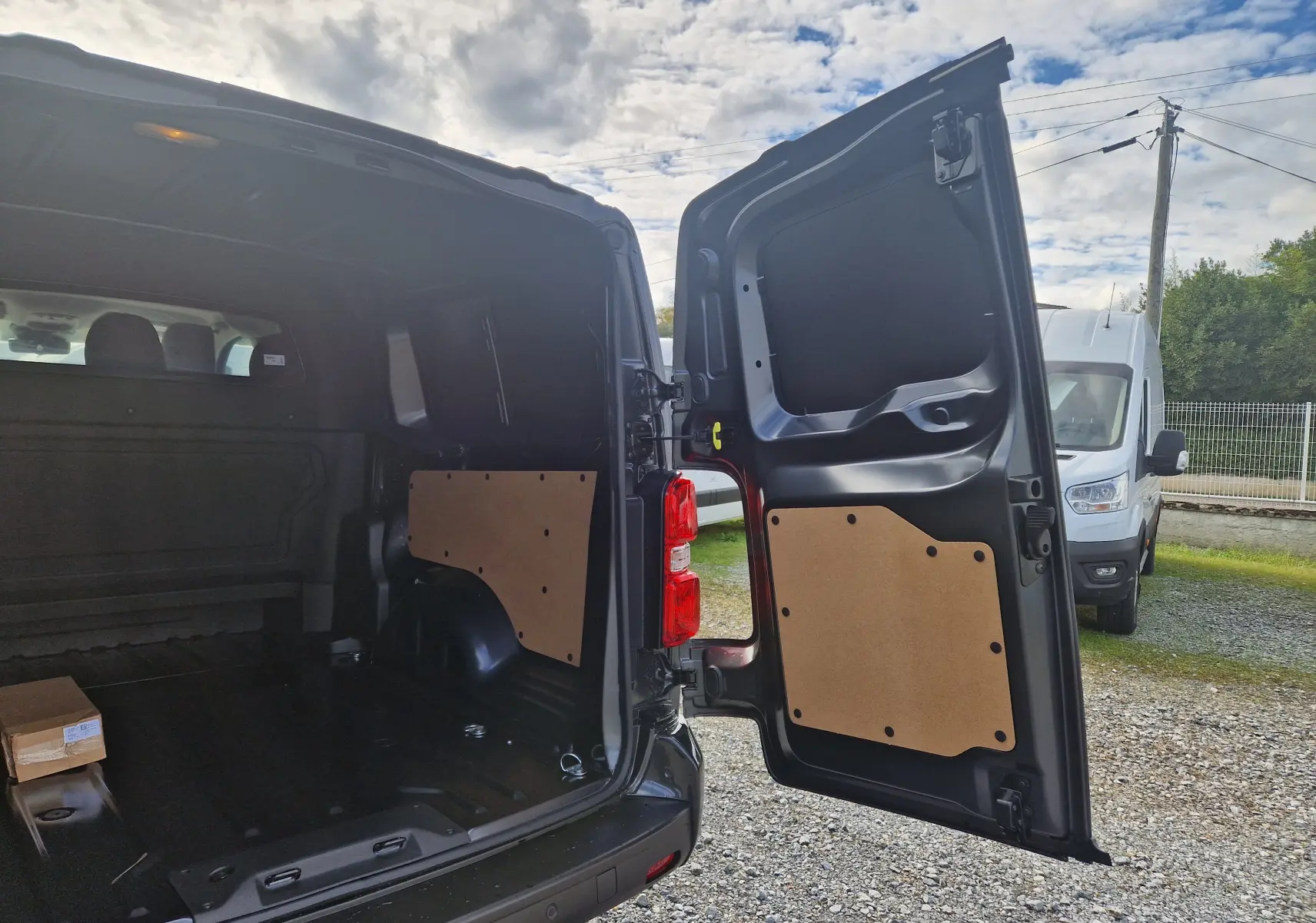 Vue arrière ouverte du Citroën Jumpy XL gris titane, montrant l'espace de chargement vide et les panneaux intérieurs en bois.