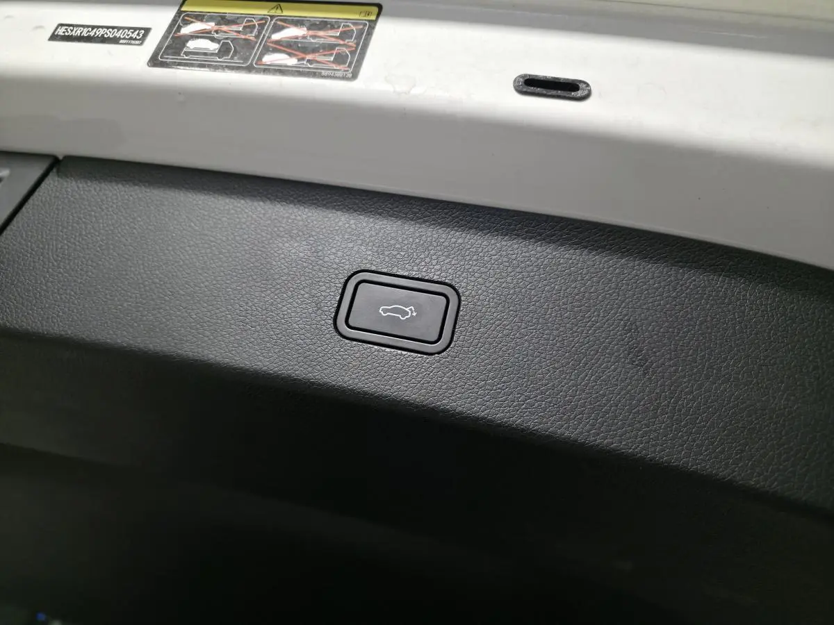 Bouton d'ouverture électrique du coffre sur la partie intérieure blanche du hayon d'une Smart #1 blanche.