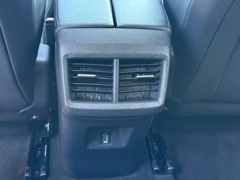 Vue rapprochée des aérateurs arrière et prise USB entre les sièges noirs du Citroën C5 Aircross gris acier 2024.