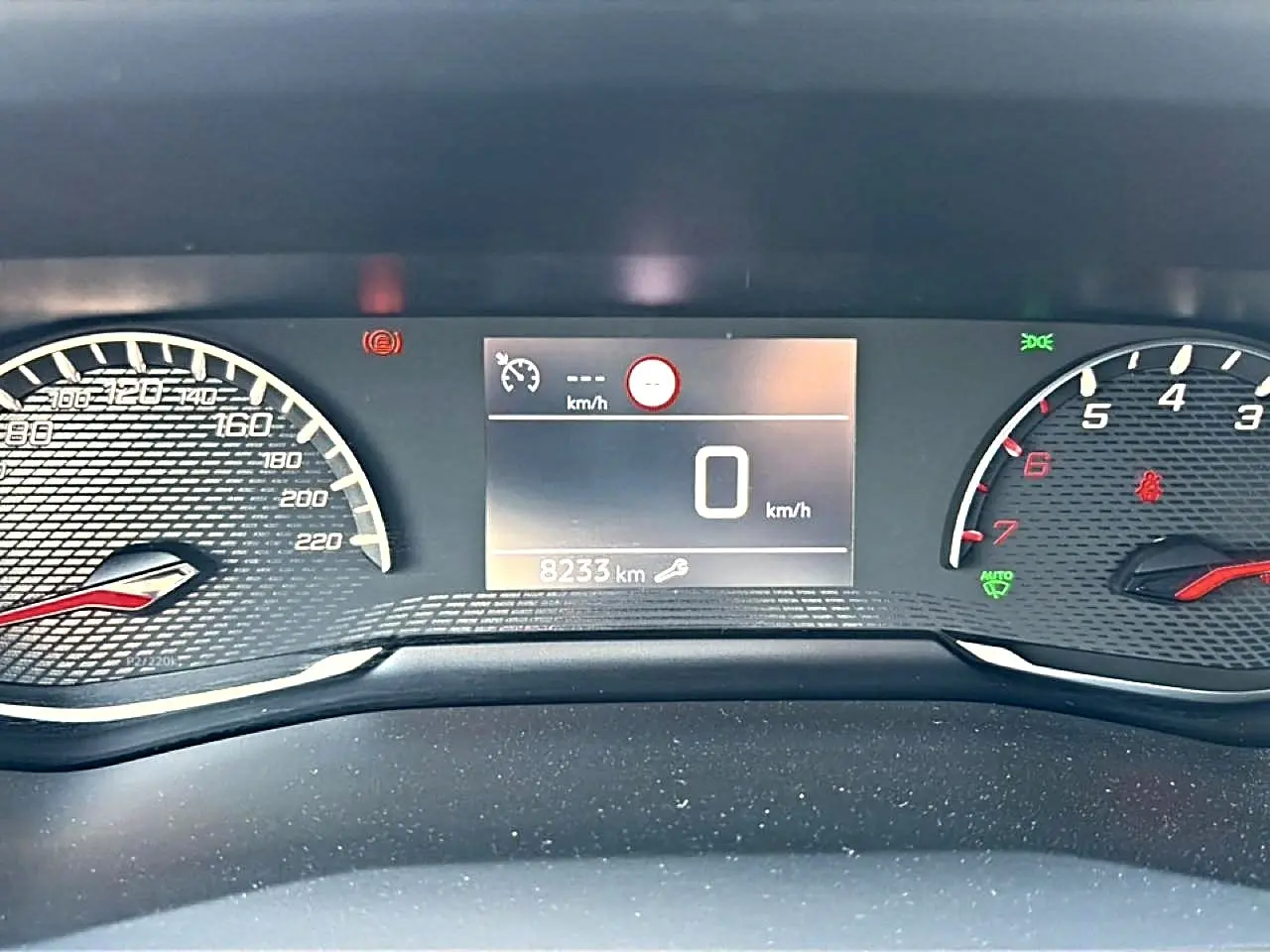 Vue rapprochée du tableau de bord numérique du Peugeot 2008 gris, affichant 0 km/h et 8233 km au compteur.