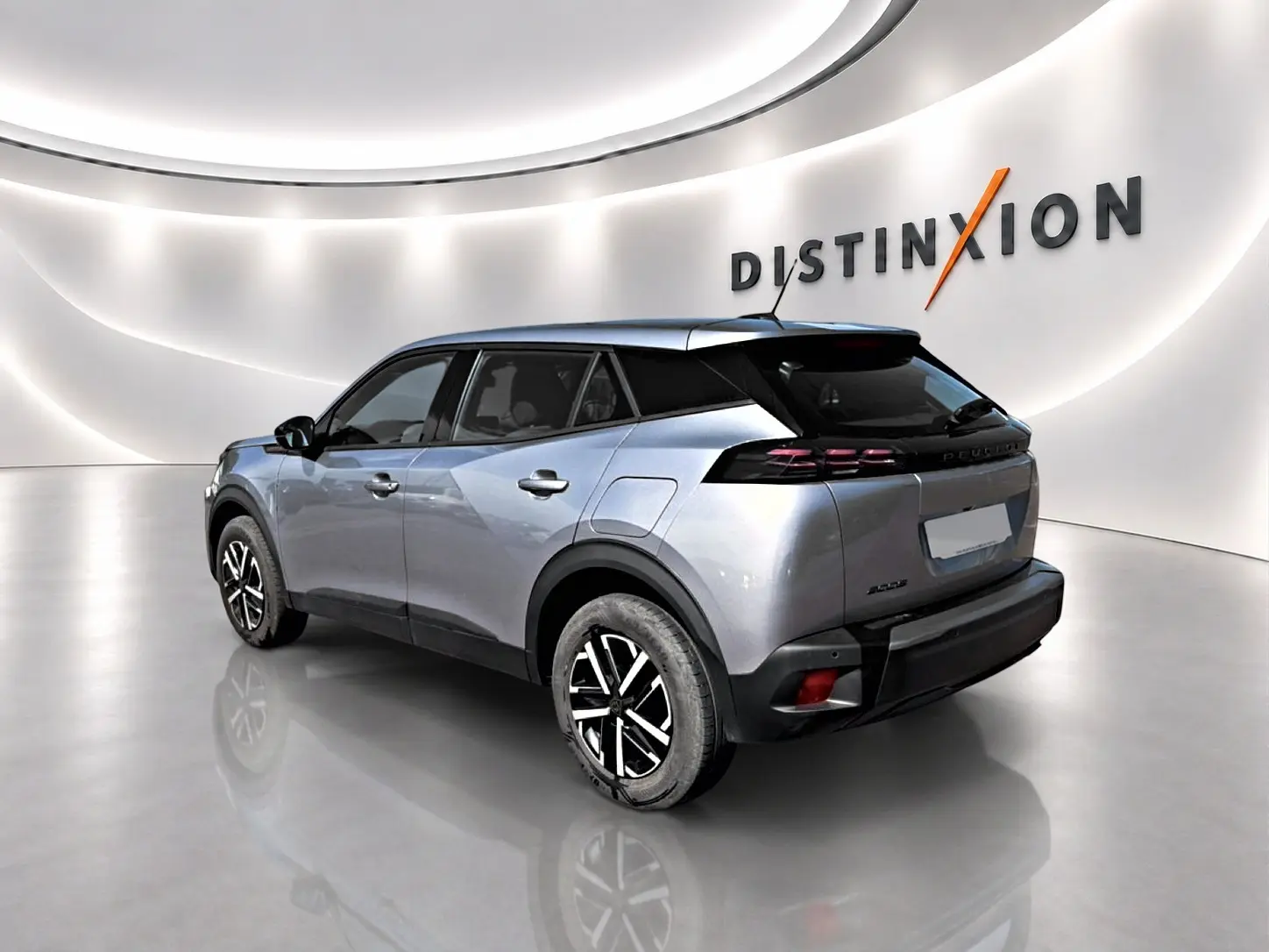 Peugeot 2008 gris en 3/4 arrière droit, avec toit noir et jantes bicolores dans un showroom lumineux.