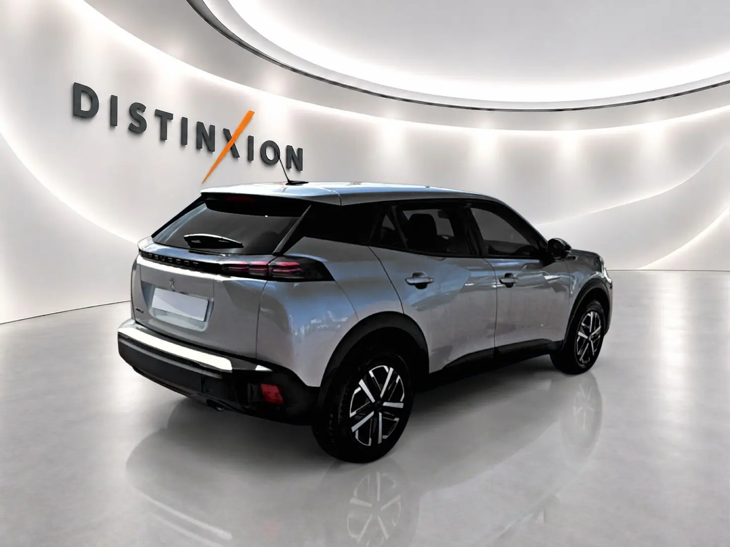 Peugeot 2008 gris en 3/4 arrière droit, avec toit noir et feux arrière LED distinctifs dans un showroom lumineux.