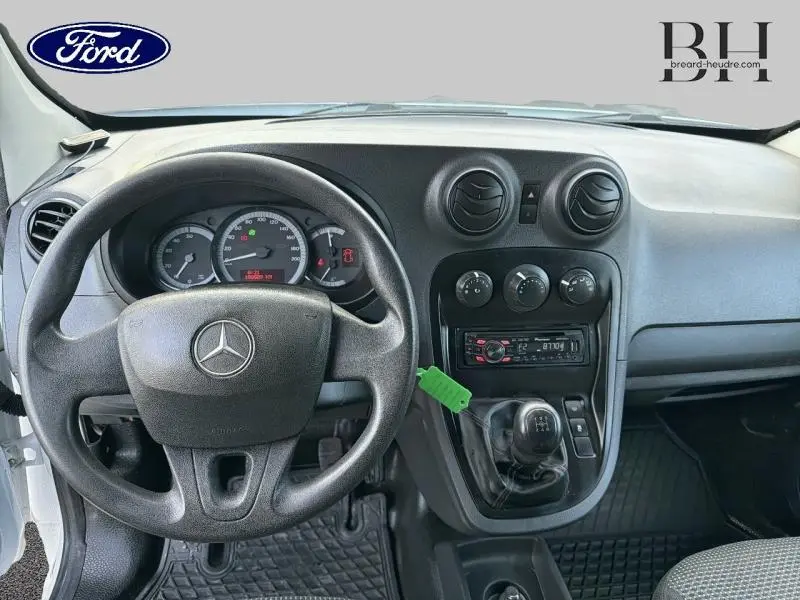 Vue intérieure avant du Mercedes Citan 108 CDI Compact blanc de 2017, montrant le volant, tableau de bord et levier de vitesses manuel.