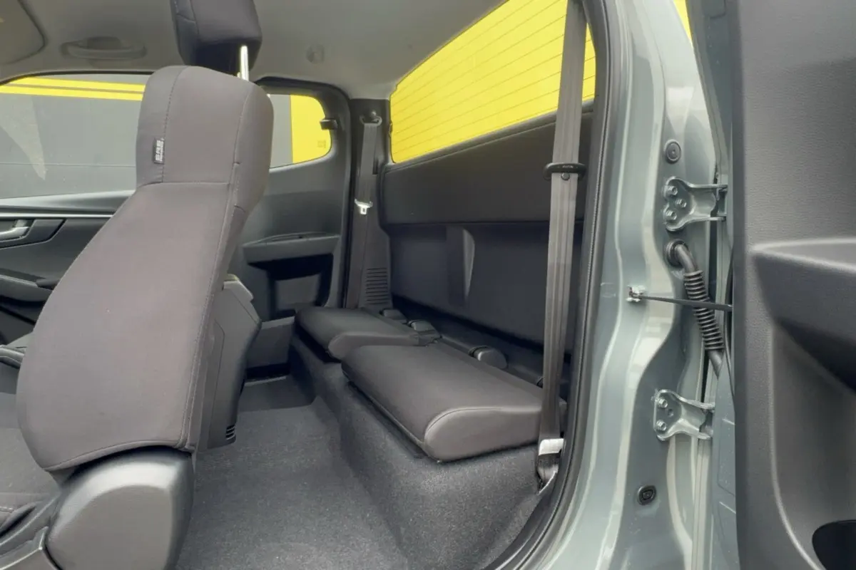 Vue intérieure arrière côté droit du pick-up Isuzu D-MAX 2026 Inishmore green metalic, sièges arrière rabattus en tissu noir.