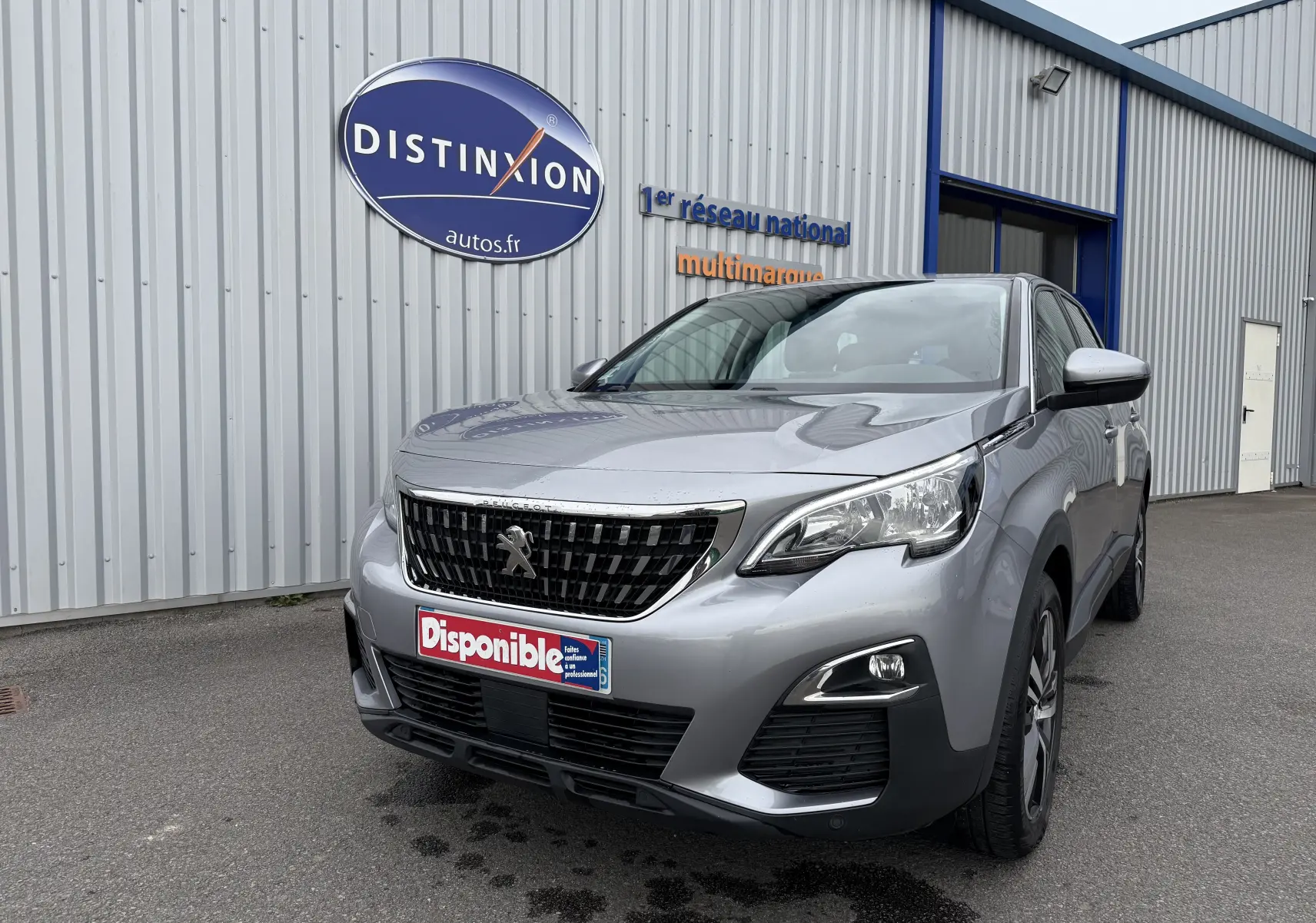 Peugeot 5008 gris Artense vue 3/4 avant droit, avec calandre noire et logo lion distinctif visible.