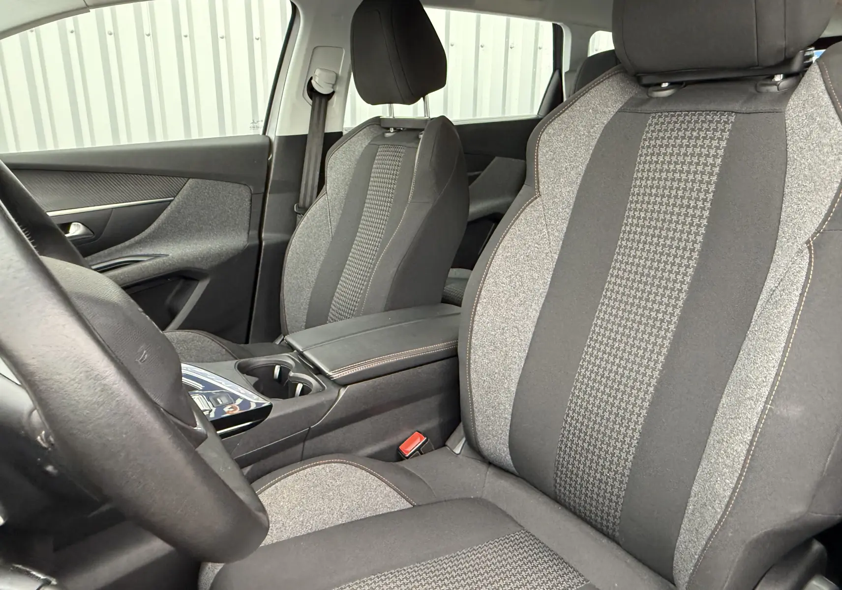Intérieur du Peugeot 5008 2020, vue côté conducteur, sièges tissu gris à motifs et console centrale noire.