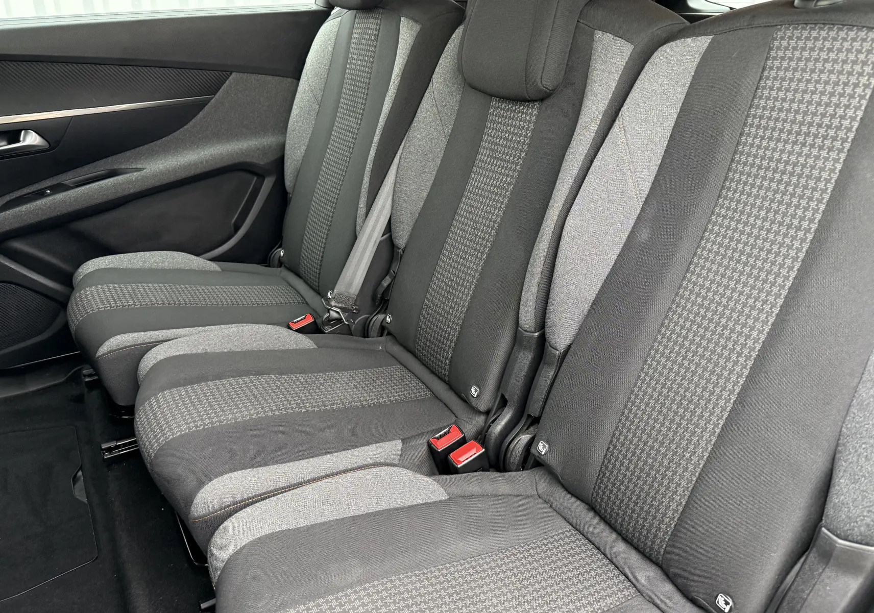 Vue latérale des sièges arrière gris foncé et clair du Peugeot 5008, mettant en valeur les ceintures de sécurité et les textures du tissu.