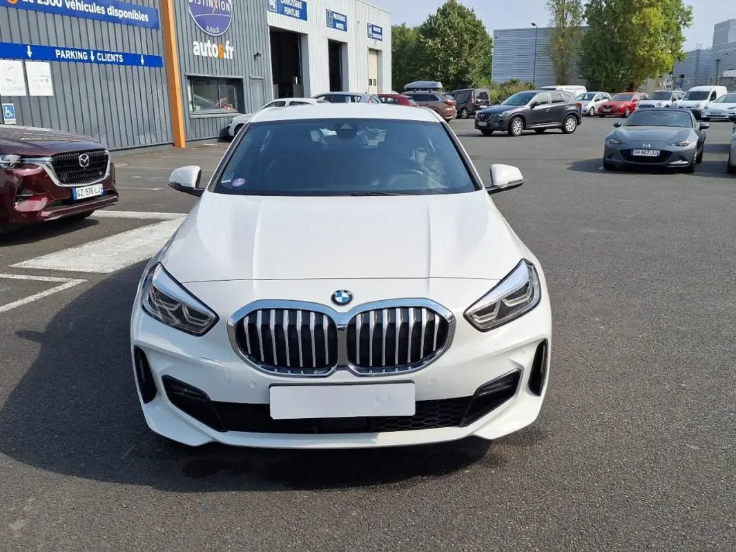 Vue frontale d'une BMW Série 1 blanche 120i M Sport avec calandre double haricot et phares LED marqués.