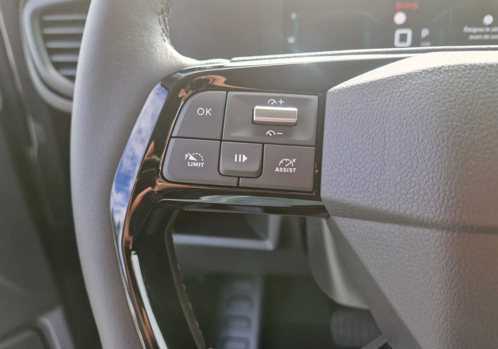 Gros plan sur les commandes au volant côté gauche du Citroën Jumpy gris titane, avec boutons de limitation et assistance de vitesse.