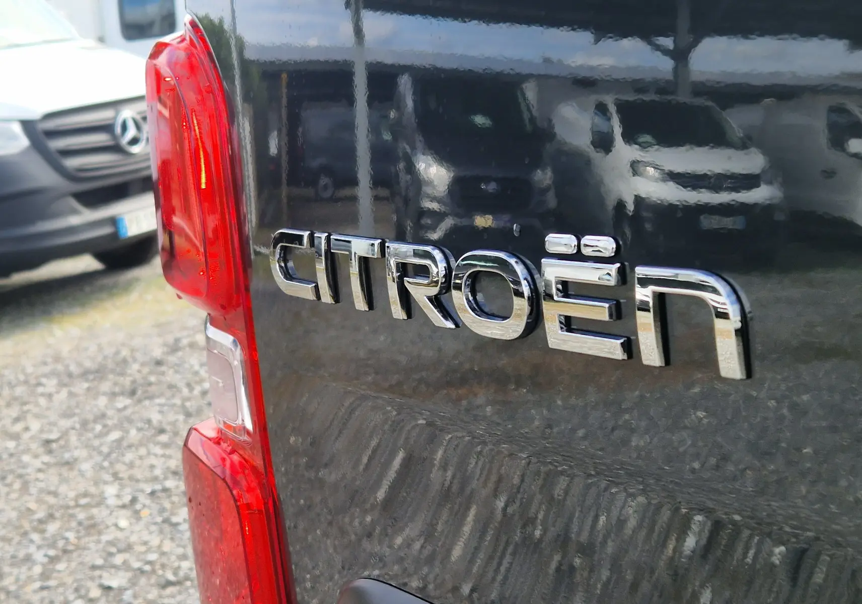 Gros plan sur le logo Citroën à l'arrière d'un Jumpy cabine approfondie gris titane, avec feu arrière rouge visible.
