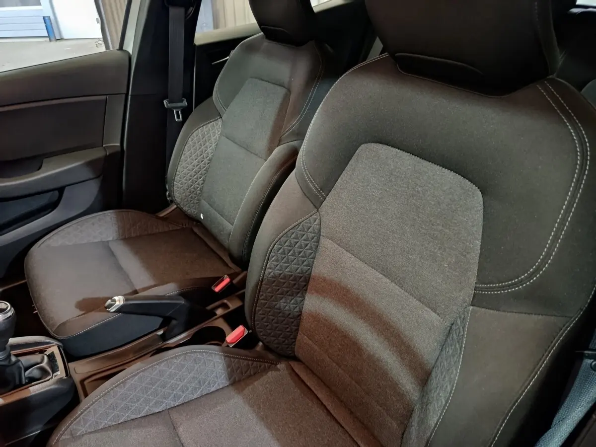 Gros plan sur les sièges avant gris foncé de la Renault Clio Equilibre TCe 90, avec coutures blanches apparentes.