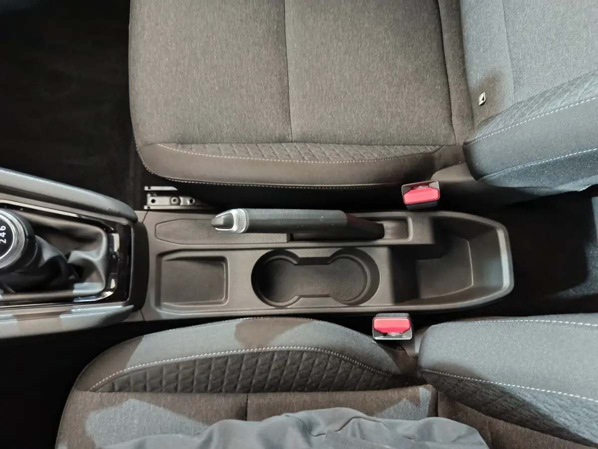 Vue plongeante sur la console centrale grise de la Renault Clio 2023, avec frein à main manuel et sièges tissu gris.