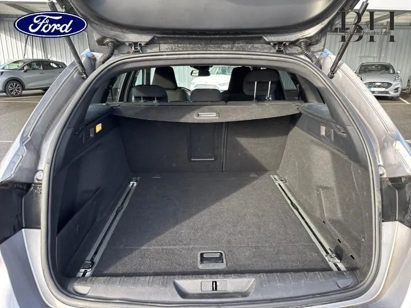Coffre ouvert vu de l'arrière d'une Peugeot 308 SW gris Artense, montrant l'espace de chargement et la tablette cache-bagages.
