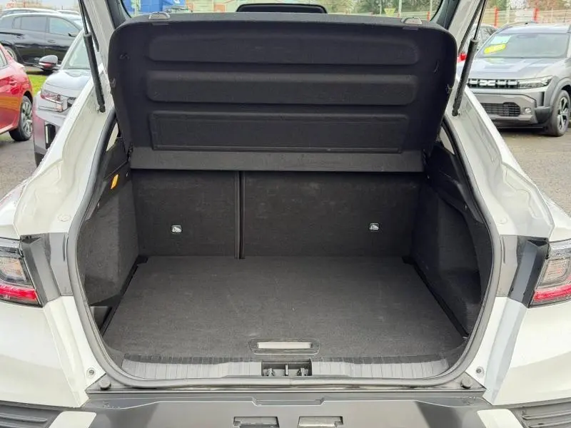Coffre ouvert vu de l'arrière d'un Renault Arkana blanc 2025, montrant l'espace de chargement vide et les garnitures noires.