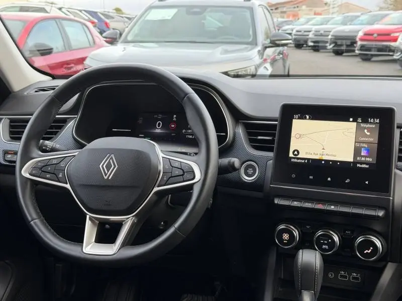Vue intérieure du tableau de bord du Renault Arkana 2025, avec volant multifonction et écran tactile central affichant la navigation.