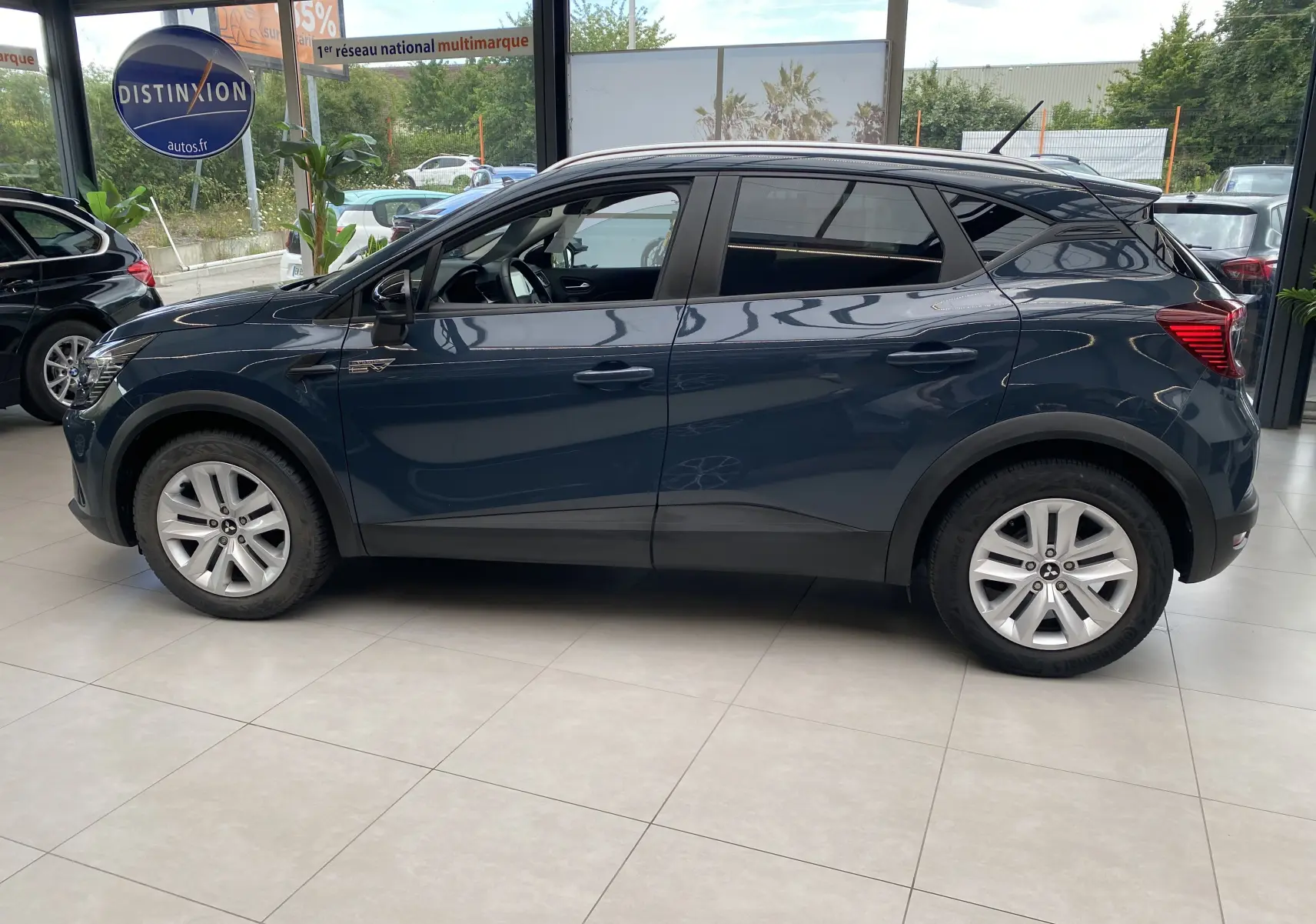 Mitsubishi ASX 2023 Steel Gray métallisé vu de profil côté gauche en showroom avec jantes alliage et vitres teintées.