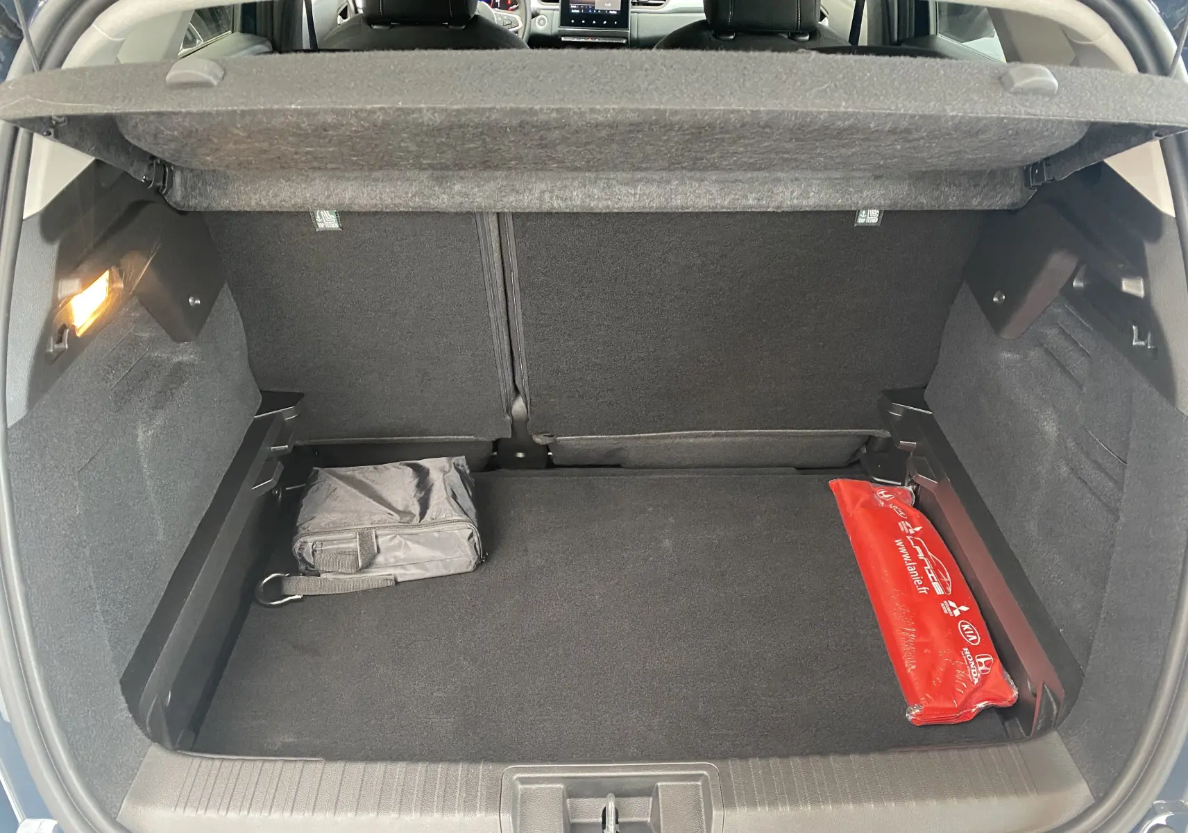 Coffre ouvert du Mitsubishi ASX 2023 Steel Gray, montrant un espace de chargement avec trousse noire et triangle de signalisation rouge.