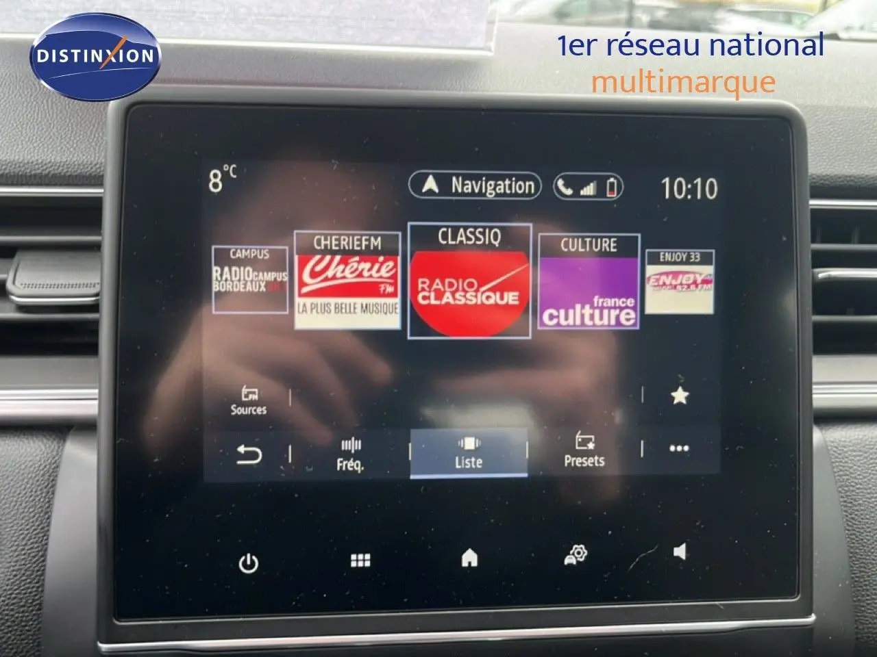 Vue rapprochée de l’écran tactile multimédia du Renault Captur 1.6 E-TECH bleu iron métal avec toit noir, affichant les radios.