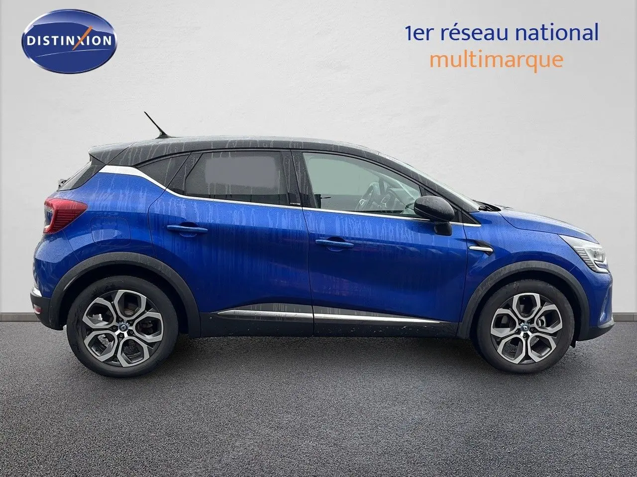 Profil droit d'un Renault Captur 1.6 E-Tech hybride rechargeable bleu iron metal avec toit noir, jantes alliage bi-ton.