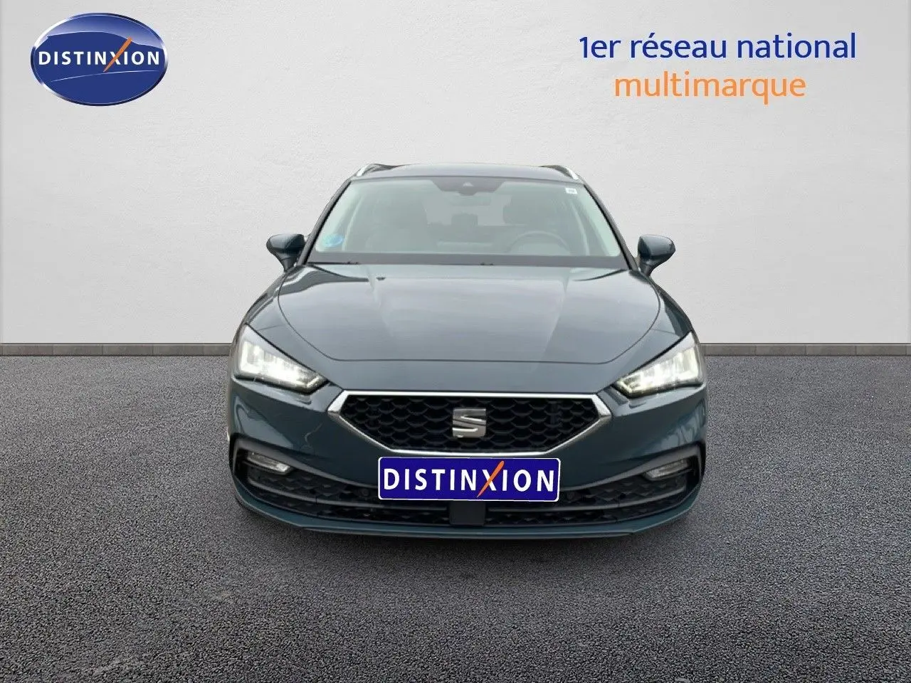 Vue avant frontale d'une SEAT LEON ST IV 1.5 TSI bleu fjord avec calandre hexagonale et phares LED allumés.