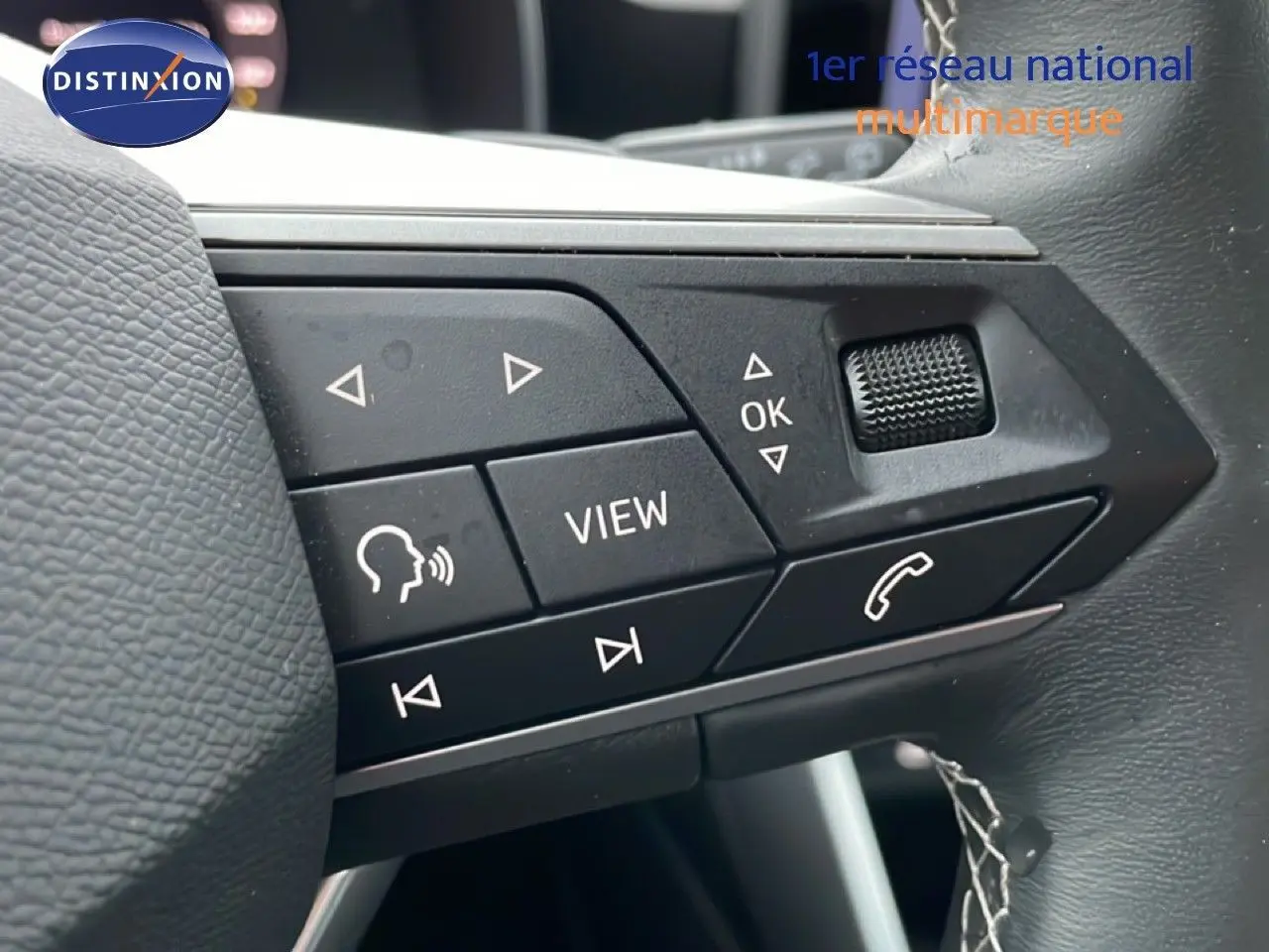 Gros plan sur les commandes multifonctions du volant en cuir noir d’une SEAT LEON ST Bleu Fjord 2025.