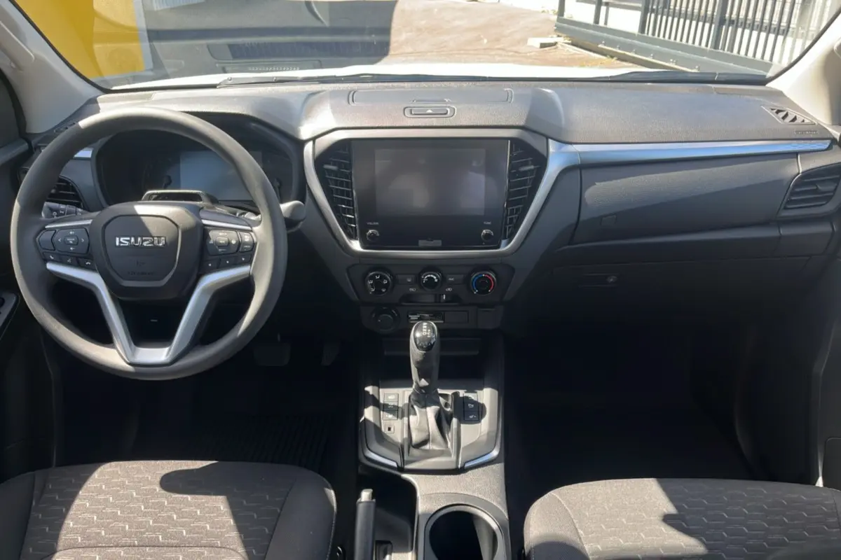 Vue intérieure avant de l'Isuzu D-MAX 2026 avec tableau de bord noir et volant multifonctions.