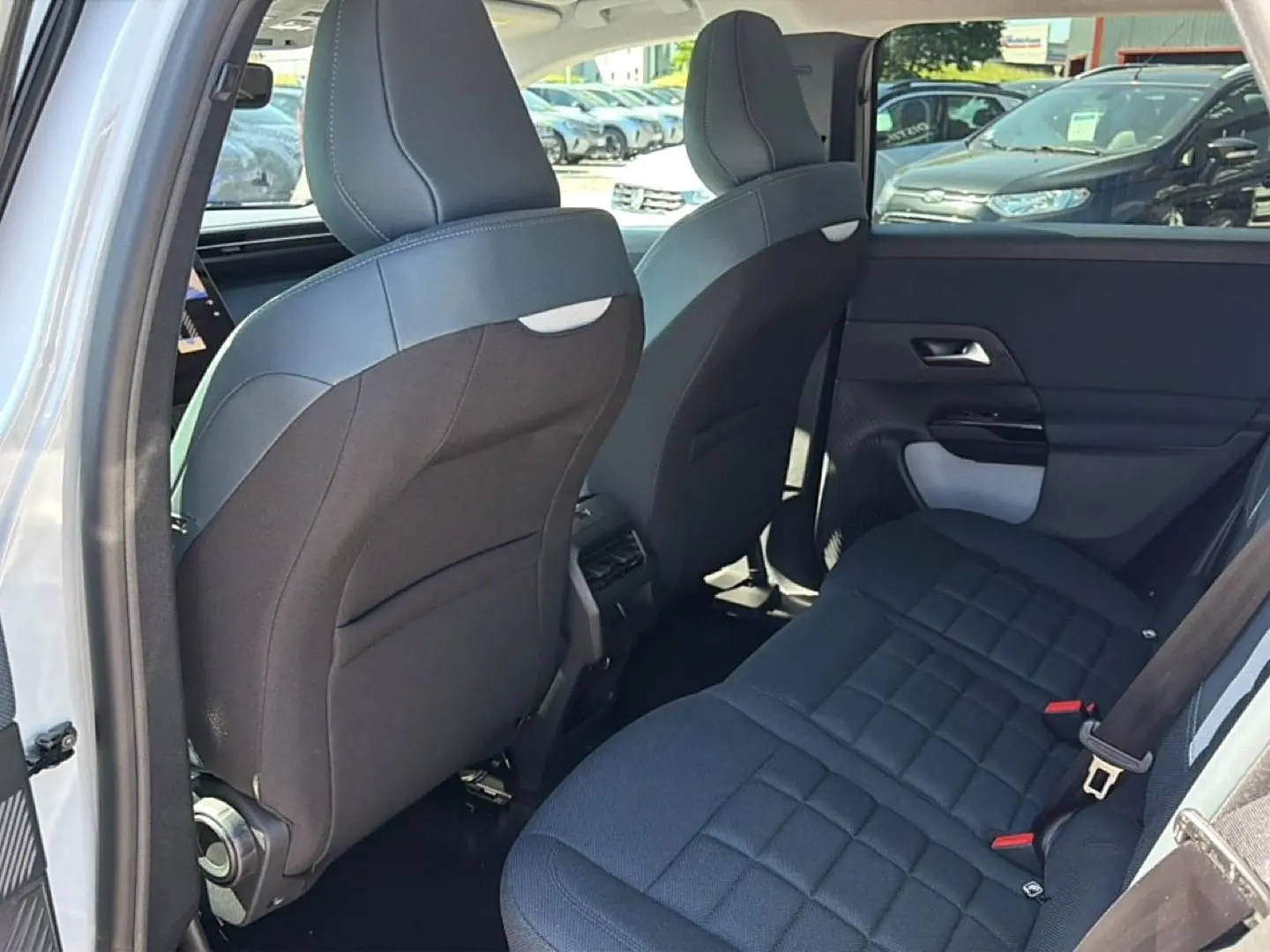Vue intérieure arrière droite du Citroën C5 Aircross blanc/noir, montrant la banquette et le dos des sièges avant noirs.