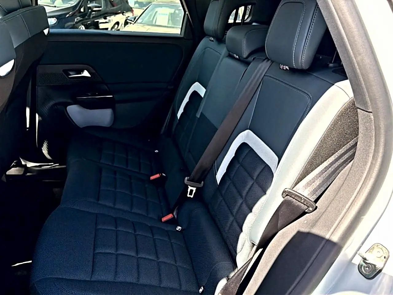 Vue intérieure arrière côté droit du Citroën C5 Aircross 2026, sièges noirs avec inserts gris et ceinture attachée.