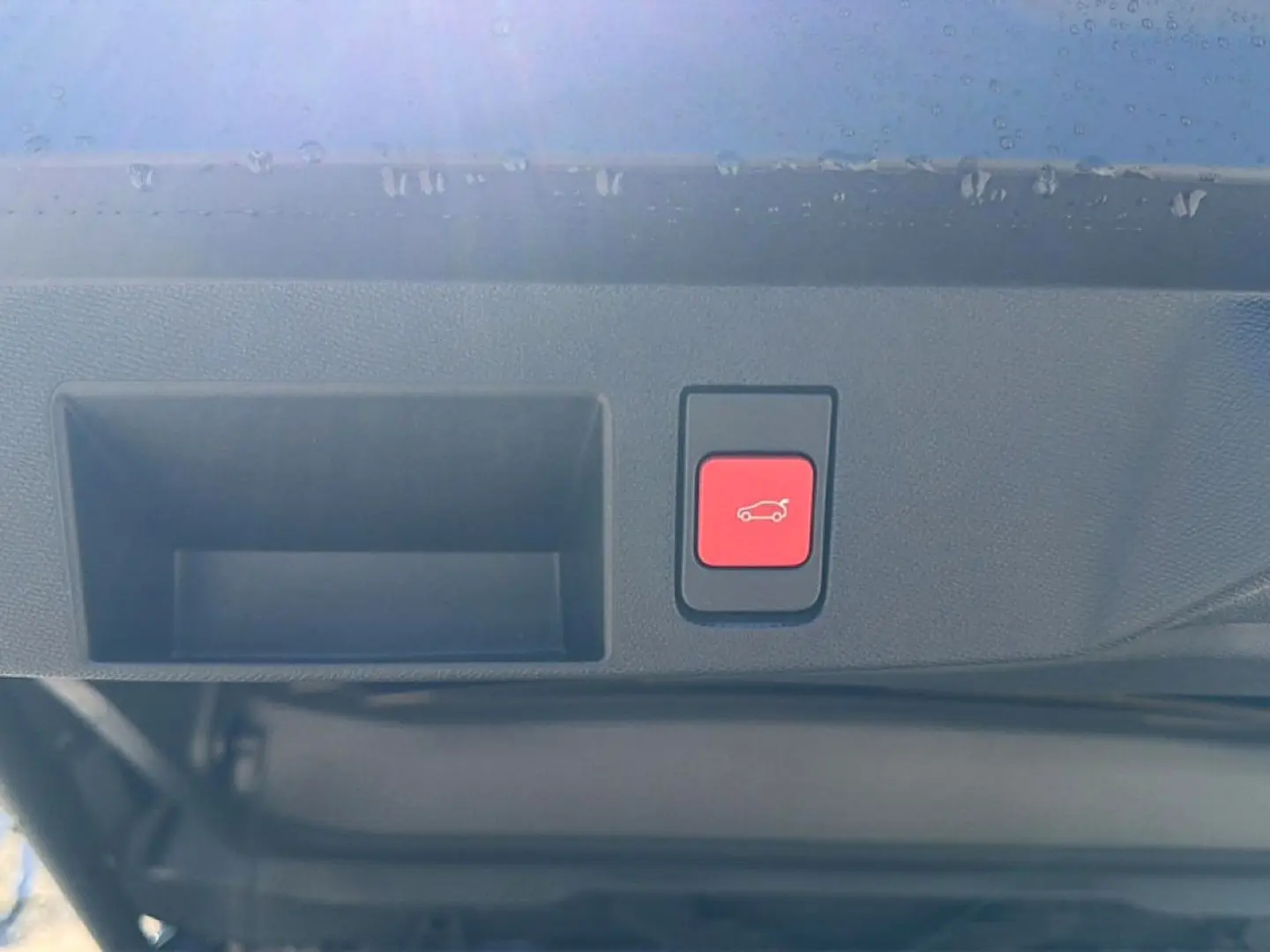 Bouton rouge d'ouverture électrique du hayon sur la partie intérieure du coffre d'un Citroën C5 Aircross blanc et noir.